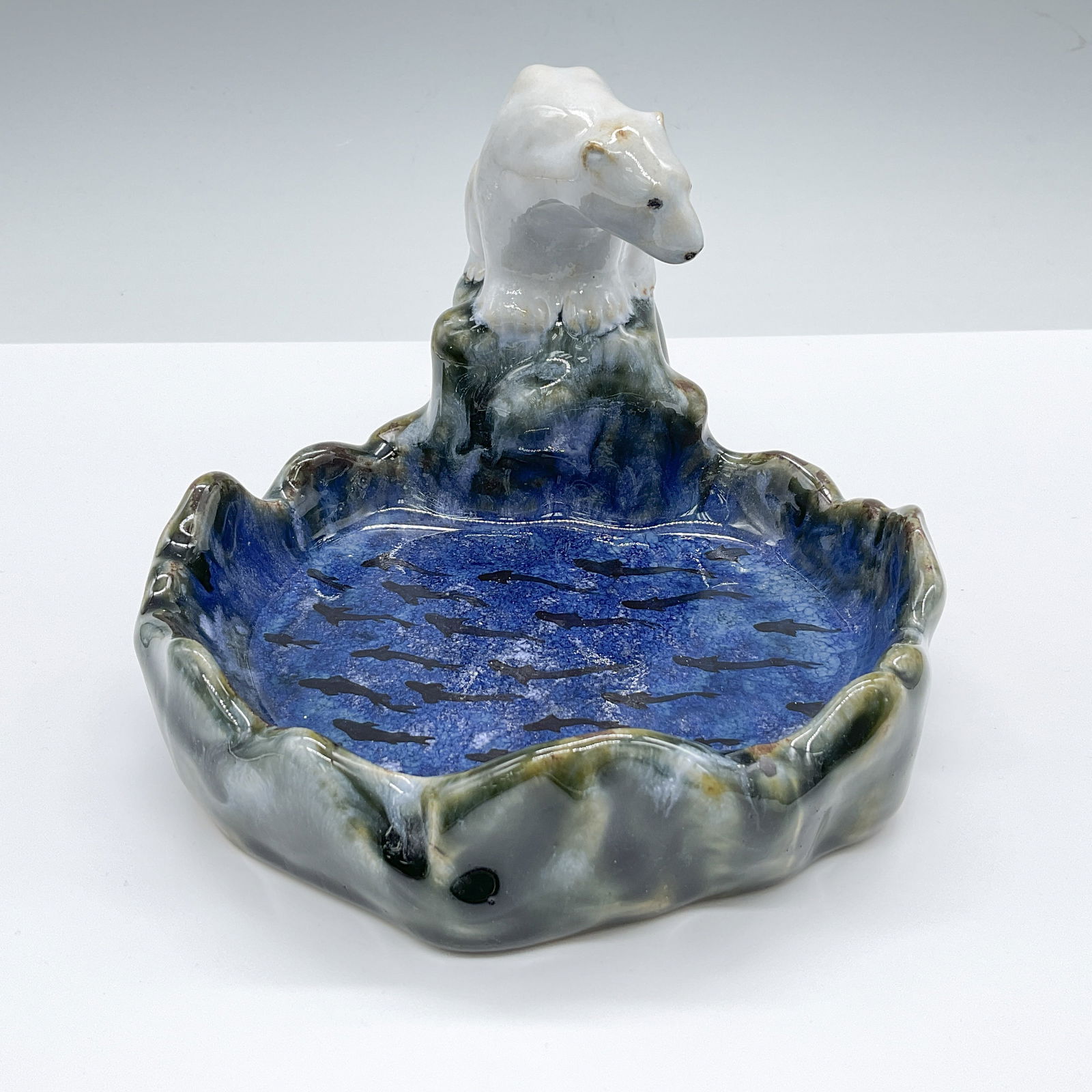 Royal Doulton Stoneware Tray, Polar Bear X8715: This handcrafted and hand-decorated English pottery tray showcases a unique design featuring a school of fish and a seated polar bear gazing at them from a rocky edge. The tray is beautifully glazed i