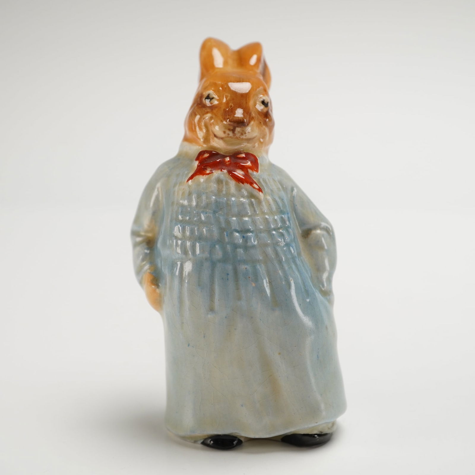 Royal Doulton Bunnykins Figurine, Reggie Bunnykin D6025: A charming Royal Doulton Bunnykins figurine designed by Charles Noke, featuring Reggie Bunnykin dressed in a blue smock with a red bow tie. Marked Doulton on the underside. Dimensions: 3.75"H Weight: