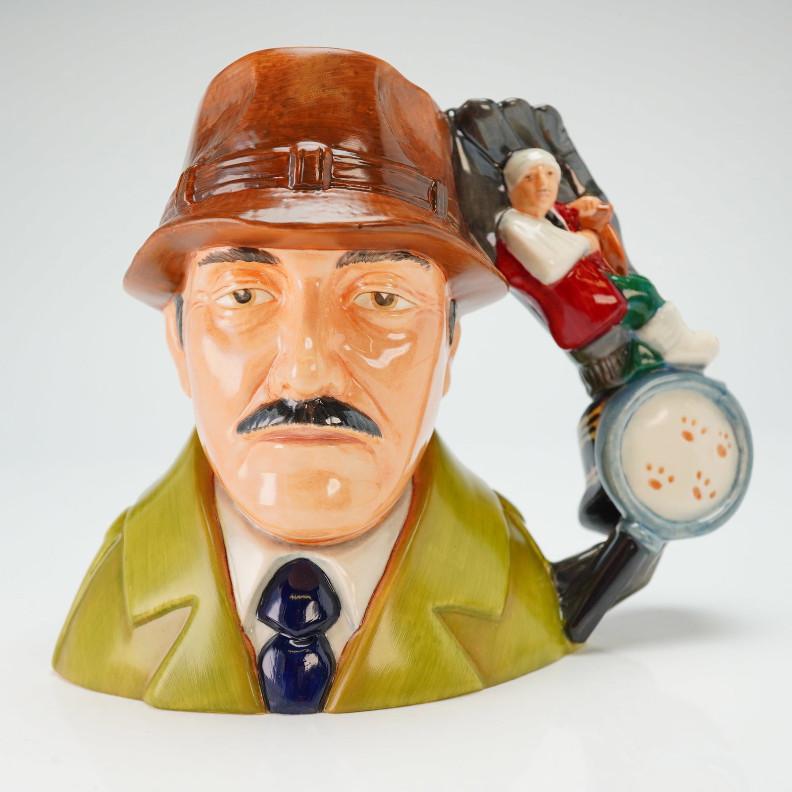 Royal Doulton Prototype Character Jug, Inspector Clouseau: Molded as Inspector Jacques Clouseau from the "The Pink Panther" series, this character jug depicts the figure in an olive-green coat, a dark-blue tie, and a brown hat. The handle is modeled with a ma