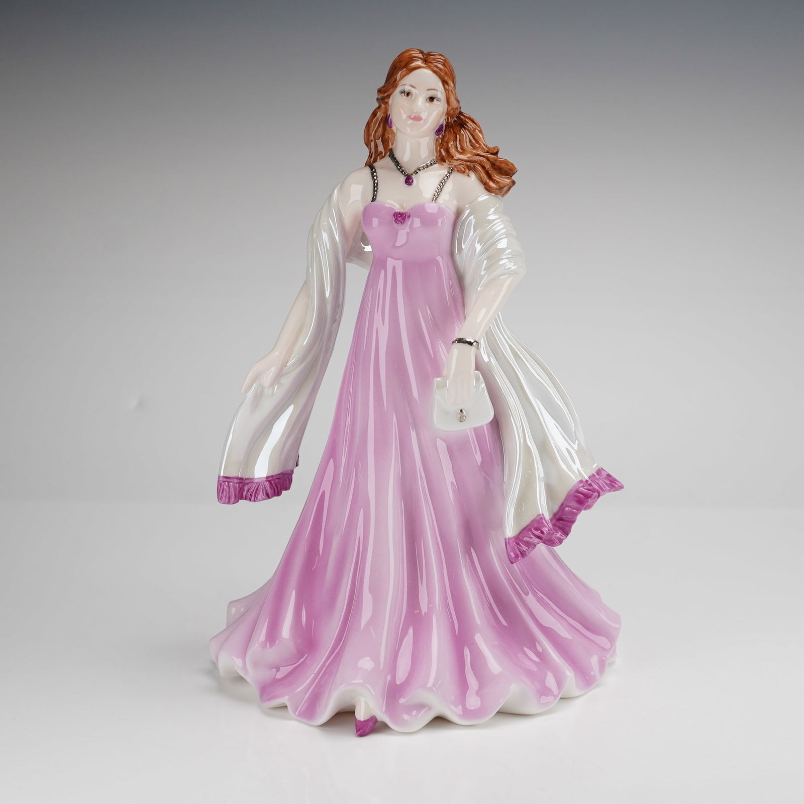 Coalport Figurine, Happy Birthday 2007: A Coalport bone china figurine modeled by Jack Glynn. This hand-decorated figure depicts a standing woman with auburn hair wearing a sleeveless, floor-length pink gown and a white wrap with a lustre f