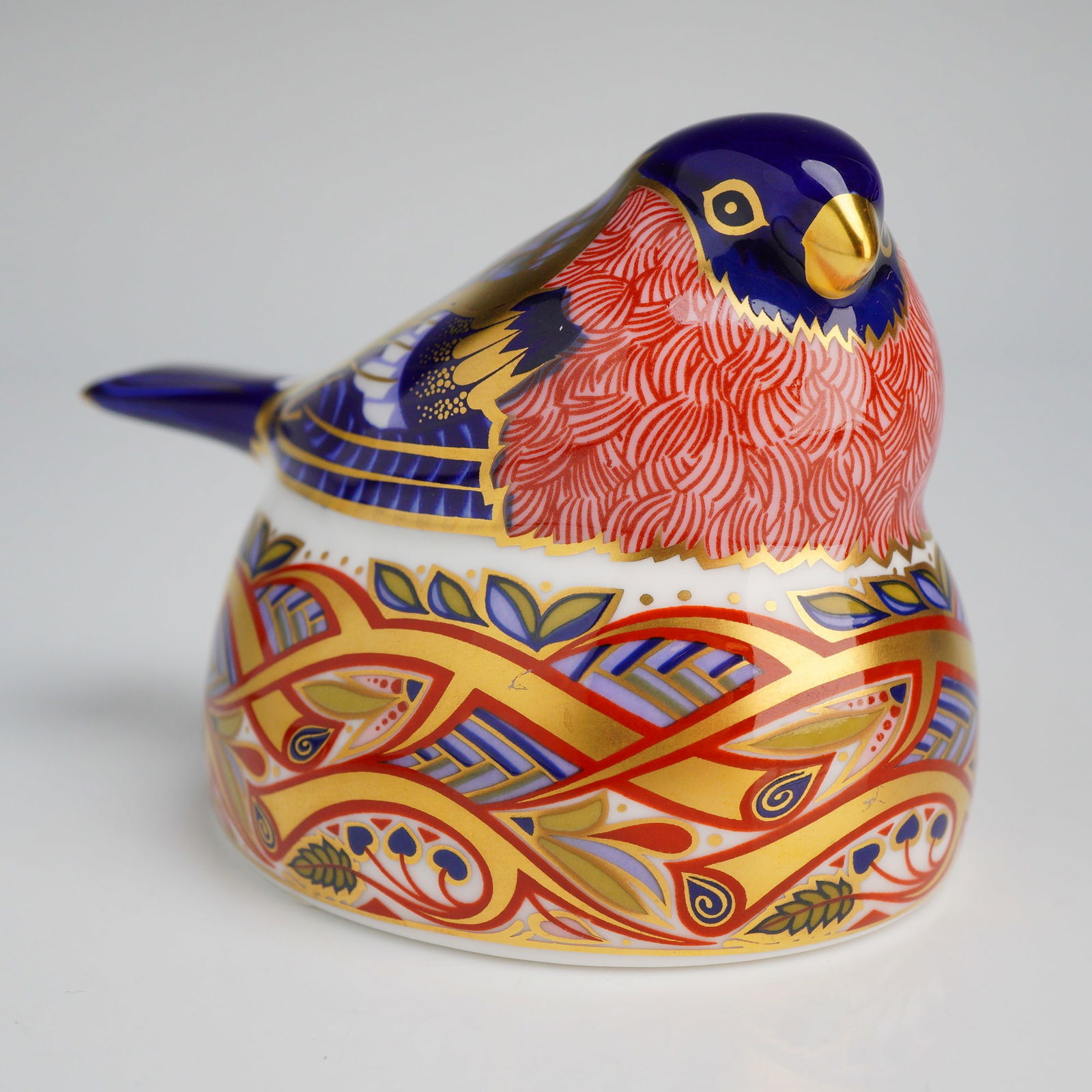 Royal Crown Derby Bullfinch Nesting Paperweight: A Royal Crown Derby English bone china paperweight titled Bullfinch Nesting. The figurine is decorated in the traditional Imari style with a palette of cobalt blue, iron red, and heavy gold gilding. T