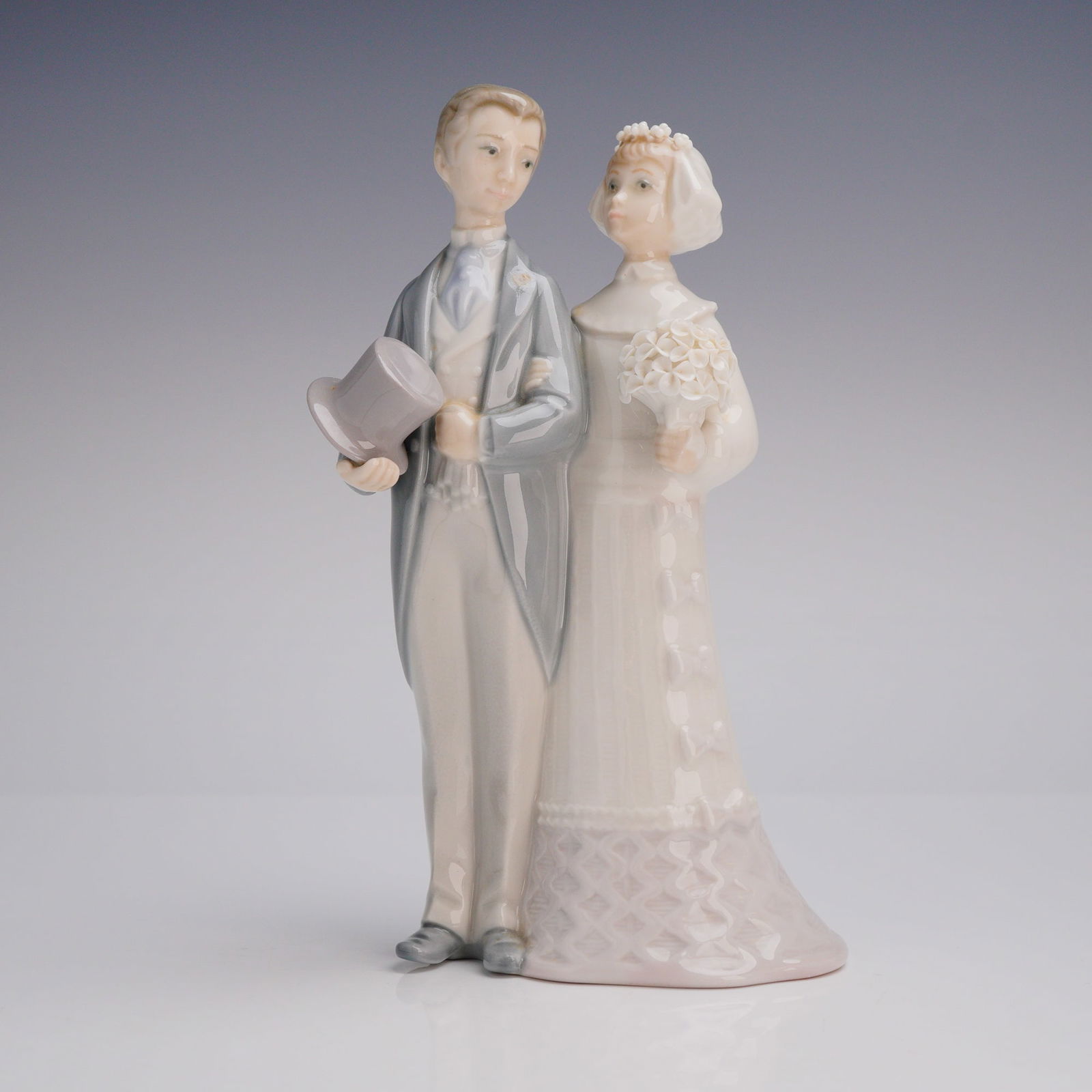 Lladro Porcelain Figurine, Wedding 1004808: A glazed porcelain figurine by Lladro, model number 4808, titled "Wedding" or "Bride and Groom." It depicts a wedding couple in a naturalistic style with the groom shown in a grey tailcoat holding a t