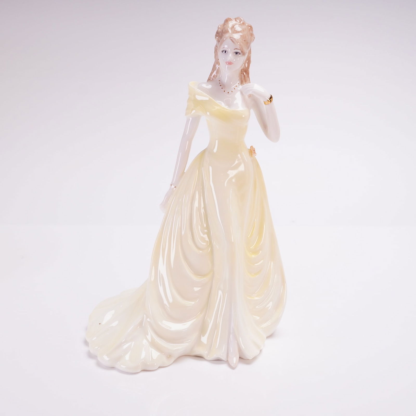 Coalport Ladies of Fashion Figurine, Susan: Coalport hand-decorated and modeled by Jack Glynn. The figure is depicted in a pale yellow off-the-shoulder ballgown featuring draped folds and a flowing skirt. The subject has styled reddish-brown ha