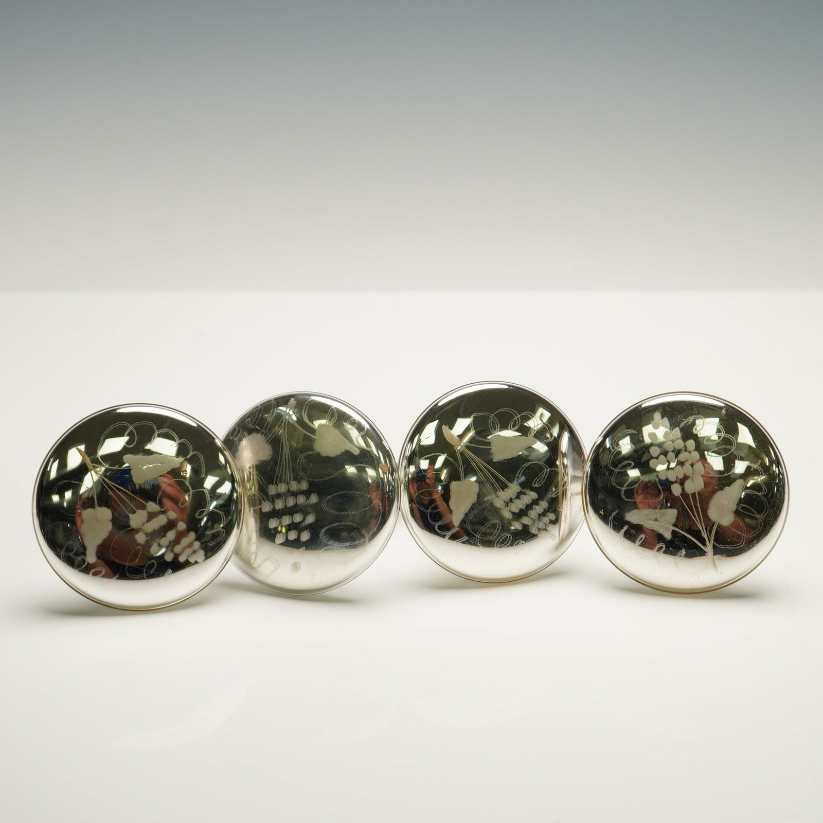 4pc Mercury Glass Grape Motif Curtain Tie Backs: Set of four vintage curtain tie backs made from mercury glass, each featuring a stylized grape motif etched into the domed face. These tie backs have a mirrored, silvery finish and are affixed with me