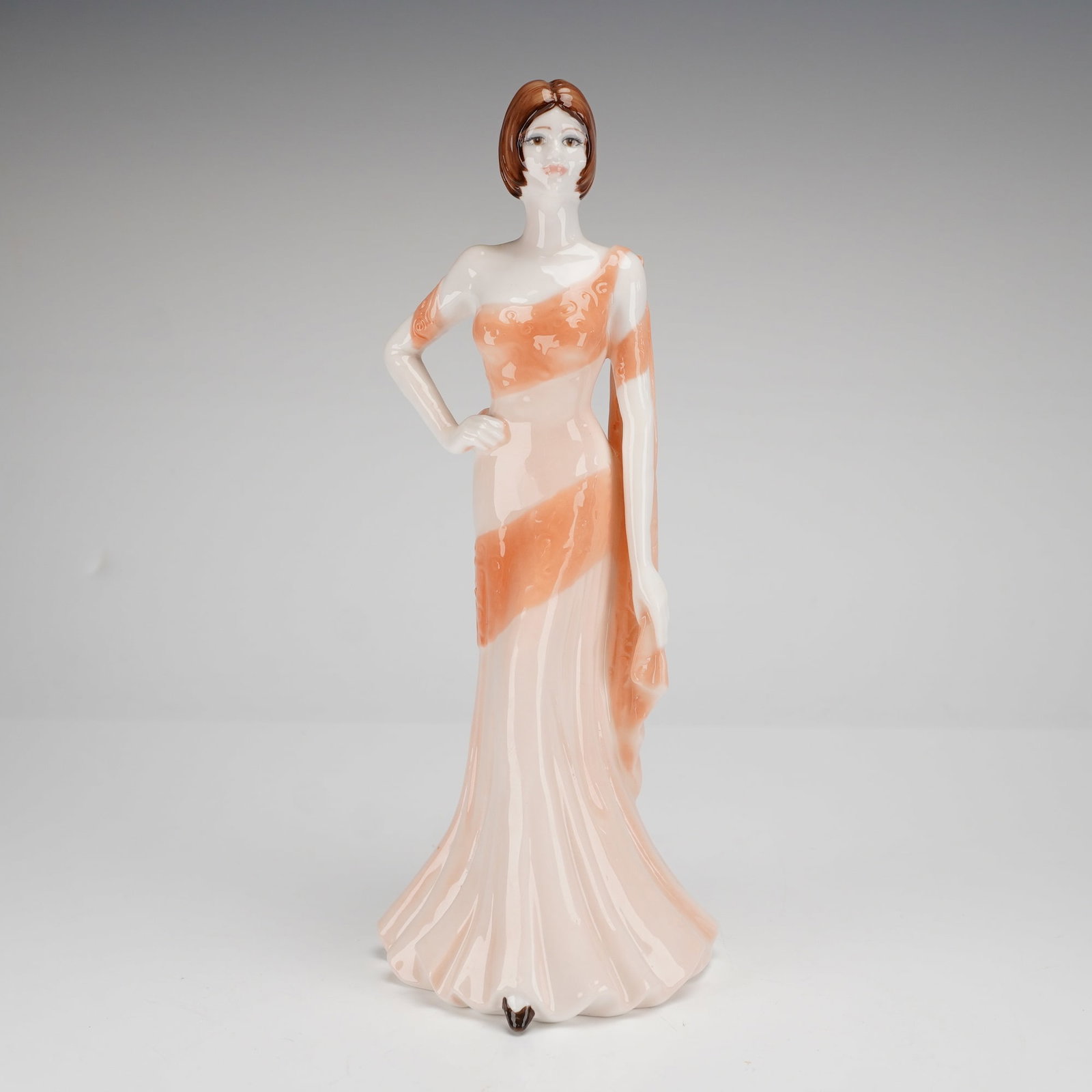 Coalport Ladies of Fashion Series Figurine, Selina: This hand-decorated piece was modeled by Jack Glynn and features a figure in a floor-length peach-toned gown accented with apricot-colored sashes and a matching shoulder drape. The woman is depicted w