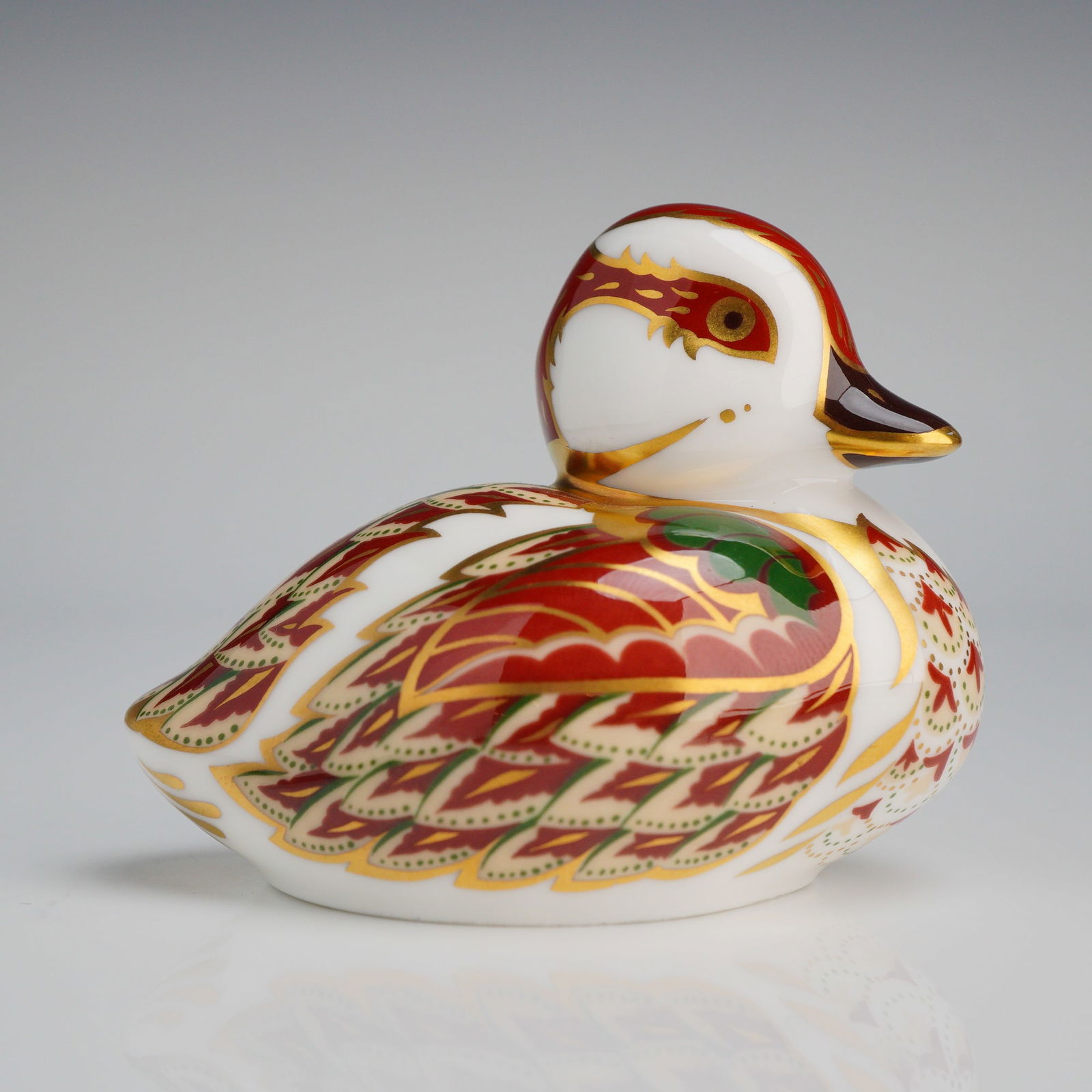 Royal Crown Derby Bakewell Duckling Paperweight: A Royal Crown Derby bone china paperweight identified as the Bakewell Duckling. The figurine is decorated in a traditional Imari style with red, green, and gold-gilded scroll and feather patterns over