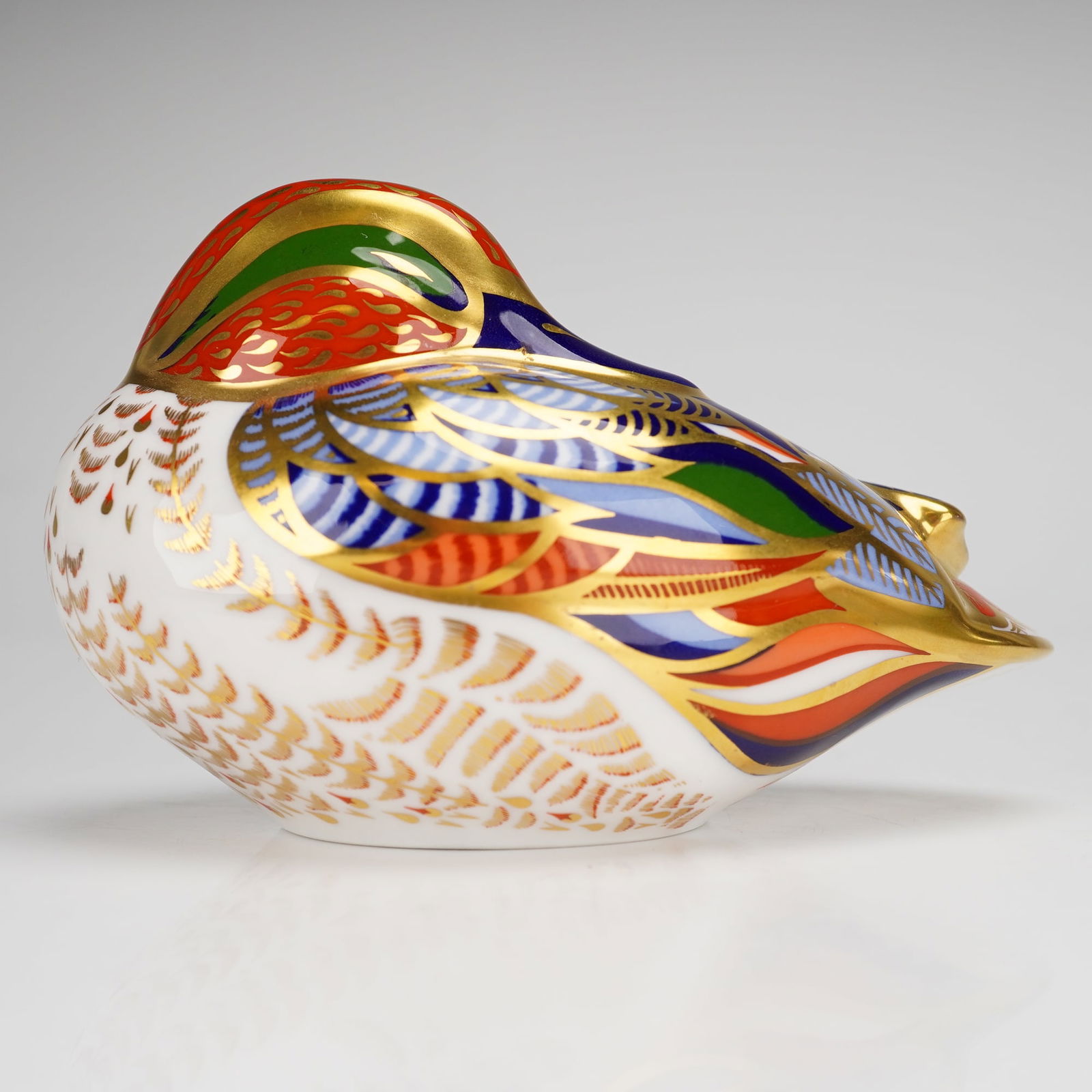 Royal Crown Derby Paperweight, Teal Duck: A Royal Crown Derby bone china paperweight depicting a Teal duck, issued as a 21st Anniversary edition. The piece is decorated in the Imari style with a palette of cobalt blue, red, green, and orange,
