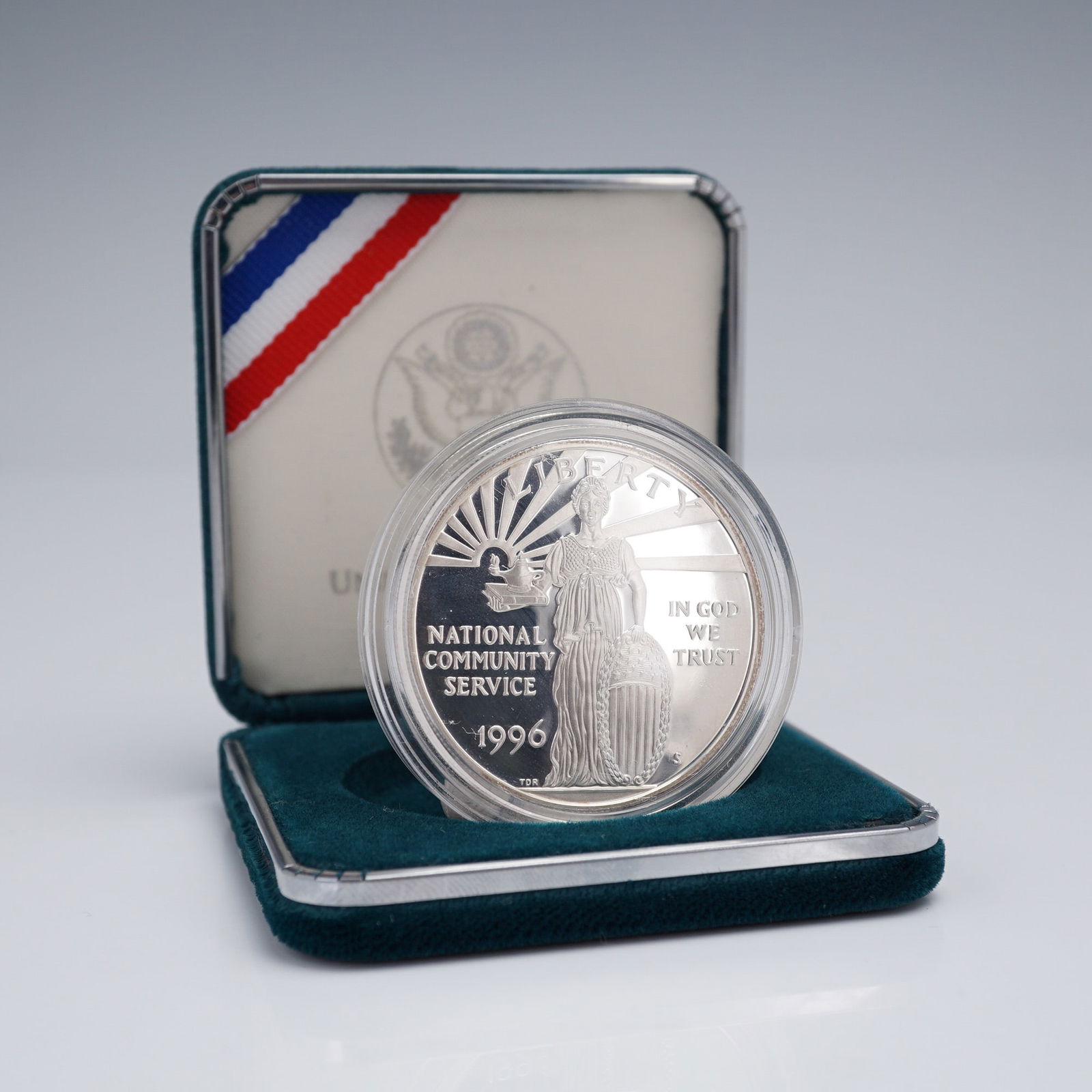 1996 National Community Service Commemorative Proof Silver Dollar: Issued by the United States Mint to honor the spirit of community service in America. The obverse features a classical allegorical female figure holding a lamp of knowledge and resting her hand on a s