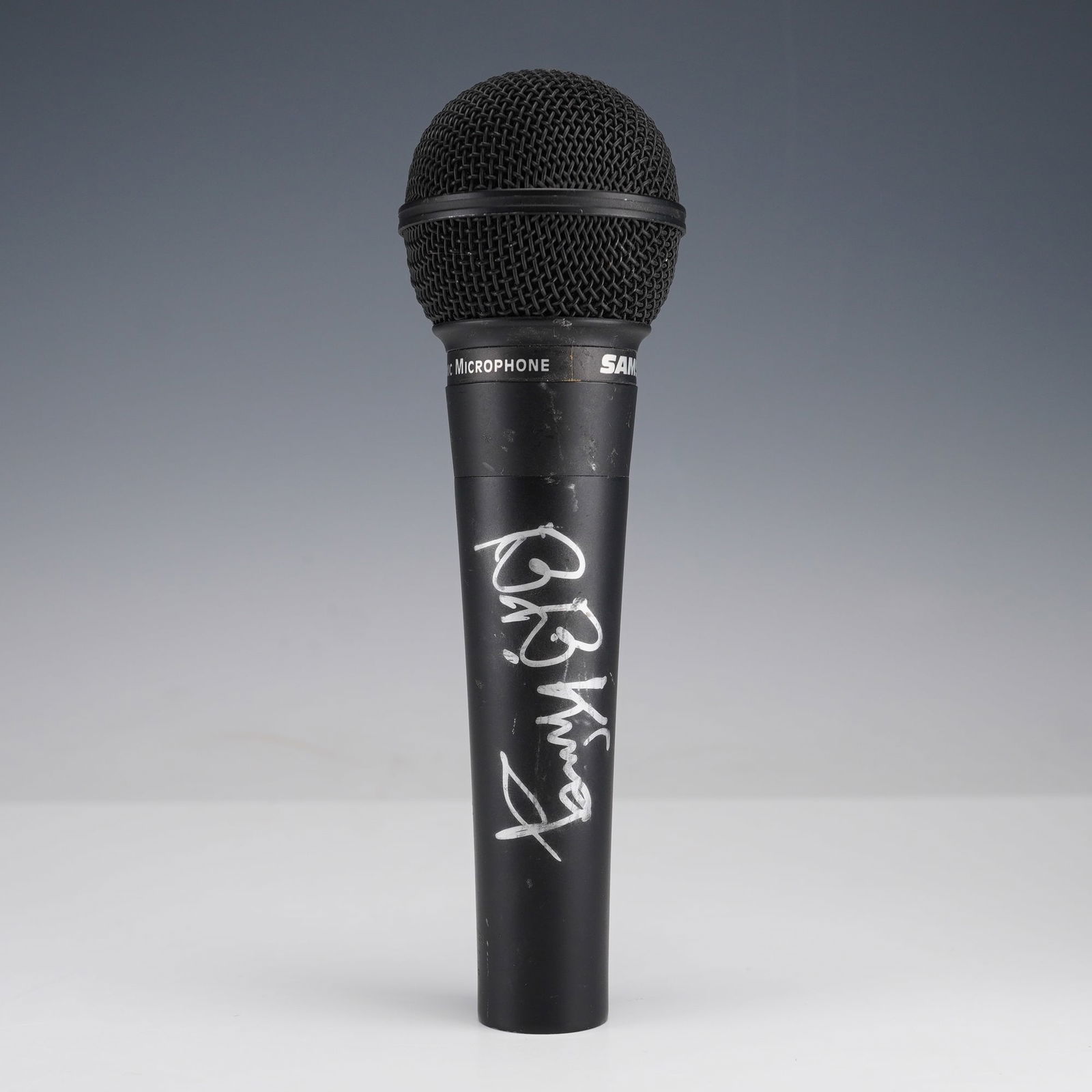 B.B. King Autographed Samson S11 Dynamic Microphone: Black Samson S11 dynamic microphone signed in silver marker by blues icon B.B. King. The autograph appears vertically along the handle in bold, clear script. King, a 15-time Grammy Award winner and Ro