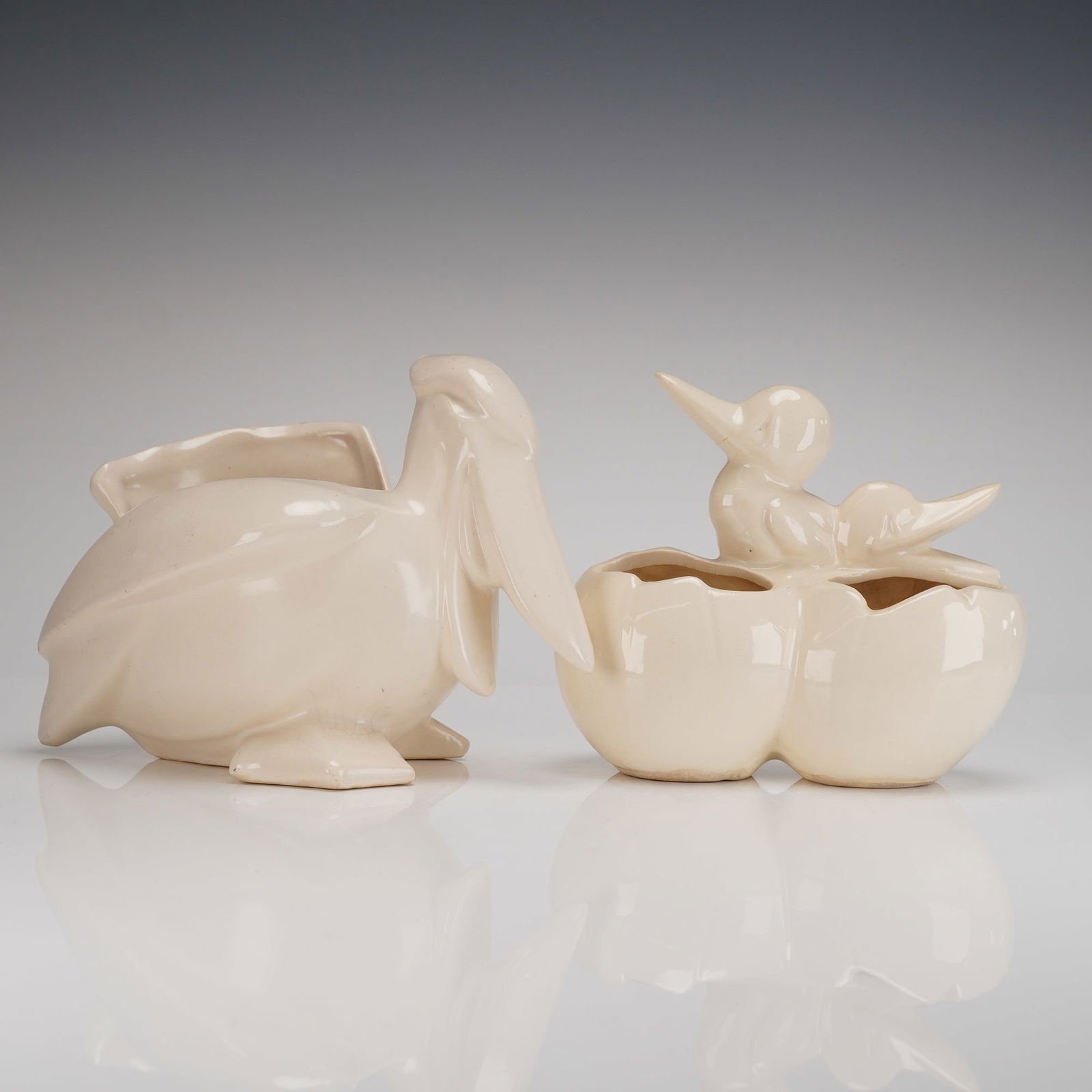 A Pair of McCoy Pottery Mid-Century Ceramic Animal Planters Pelican: A pair of 2pc. Mid-Century Modern ceramic planters attributed to McCoy Pottery, circa 1940s-1950s. The vessels are constructed of molded earthenware and finished in a uniform, high-gloss cream or ivor