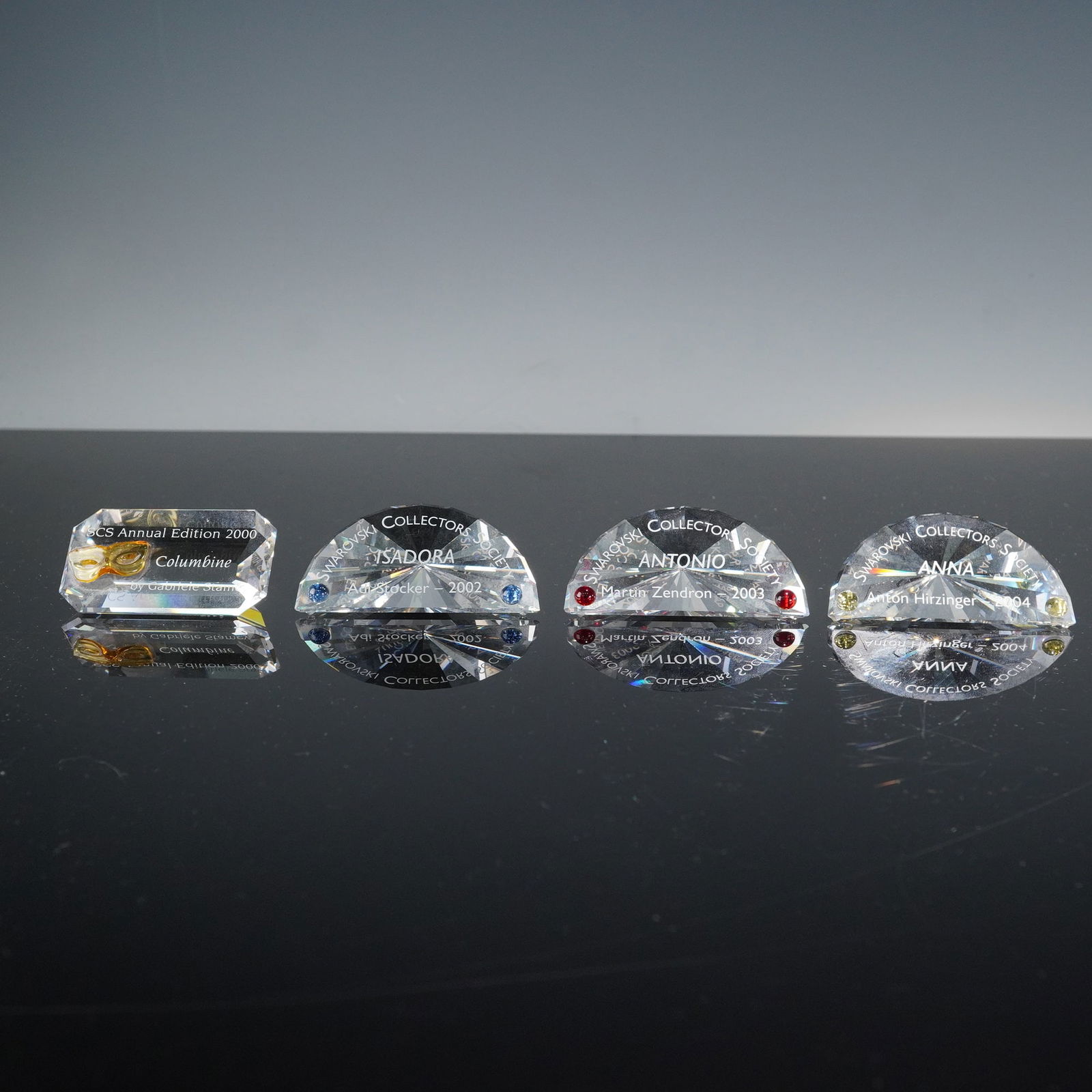 4pc Swarovski Crystal Collectors Society Plaques: A refined collection of four Swarovski crystal collector plaques, each etched with identifying details for Annual Editions Columbine (2000), Isadora (2002), Antonio (2003), and Anna (2004). Each plaqu