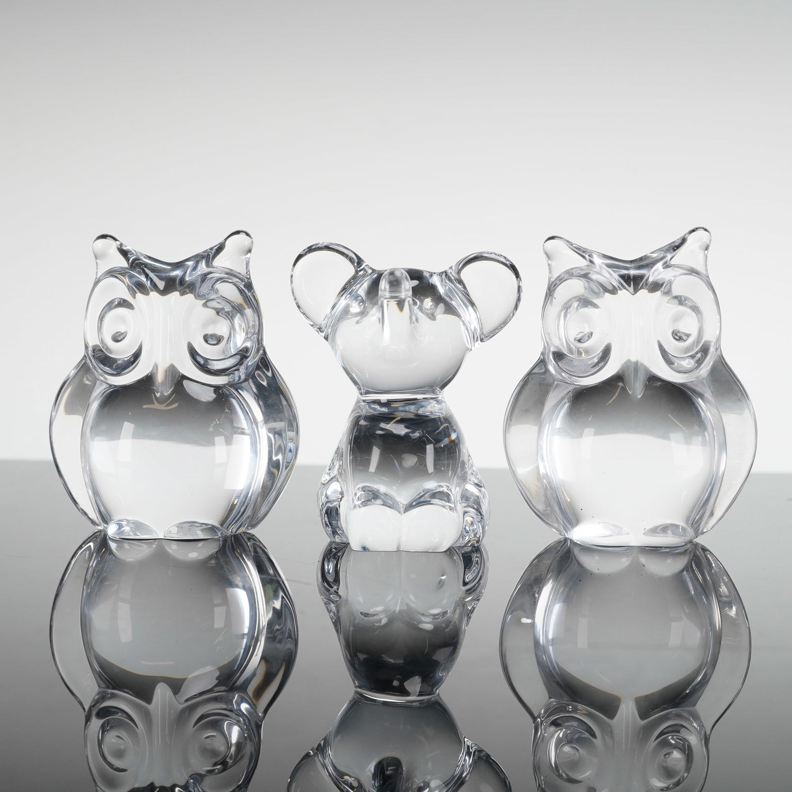 3pc Crystal Animal Paperweights: Collection consisting of three clear crystal figures including a pair of owls with feather tufts on the head and round eyes, and a seated elephant with trunk raised; maker's mark to bottom base. Dimen