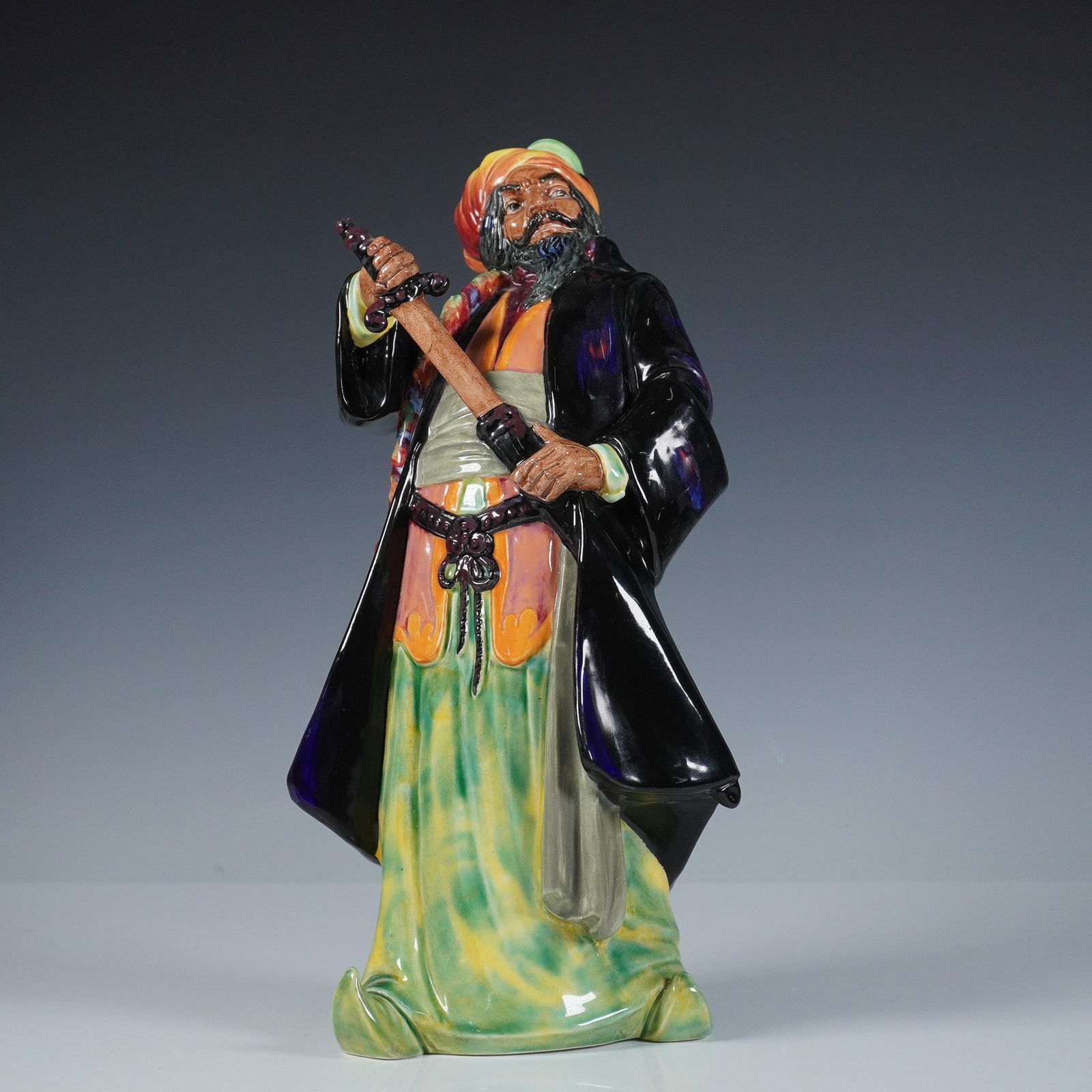 Royal Doulton Figurine, Blue Beard HN2105: Royal Doulton figurine titled Blue Beard, model HN2105, depicting the legendary character in vibrant multicolored robes and a dramatic pose holding a sword. Designed by Leslie Harradine and issued in