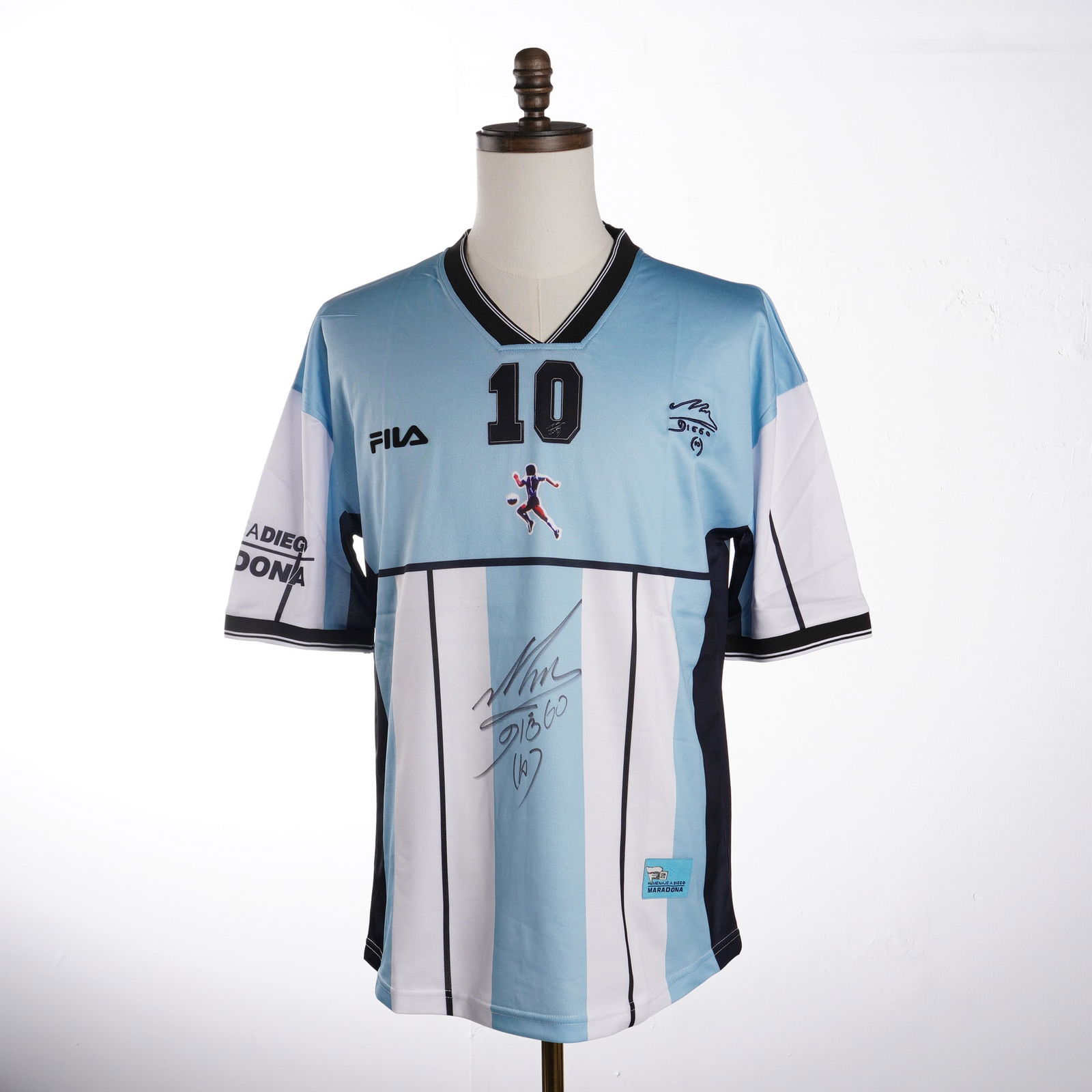 Diego Maradona Signed 2001 Argentina Farewell Jersey: This lot features an Argentina National Team commemorative testimonial shirt produced by Fila for Diego Maradona's 2001 farewell match. The jersey is designed with light blue and white vertical stripe