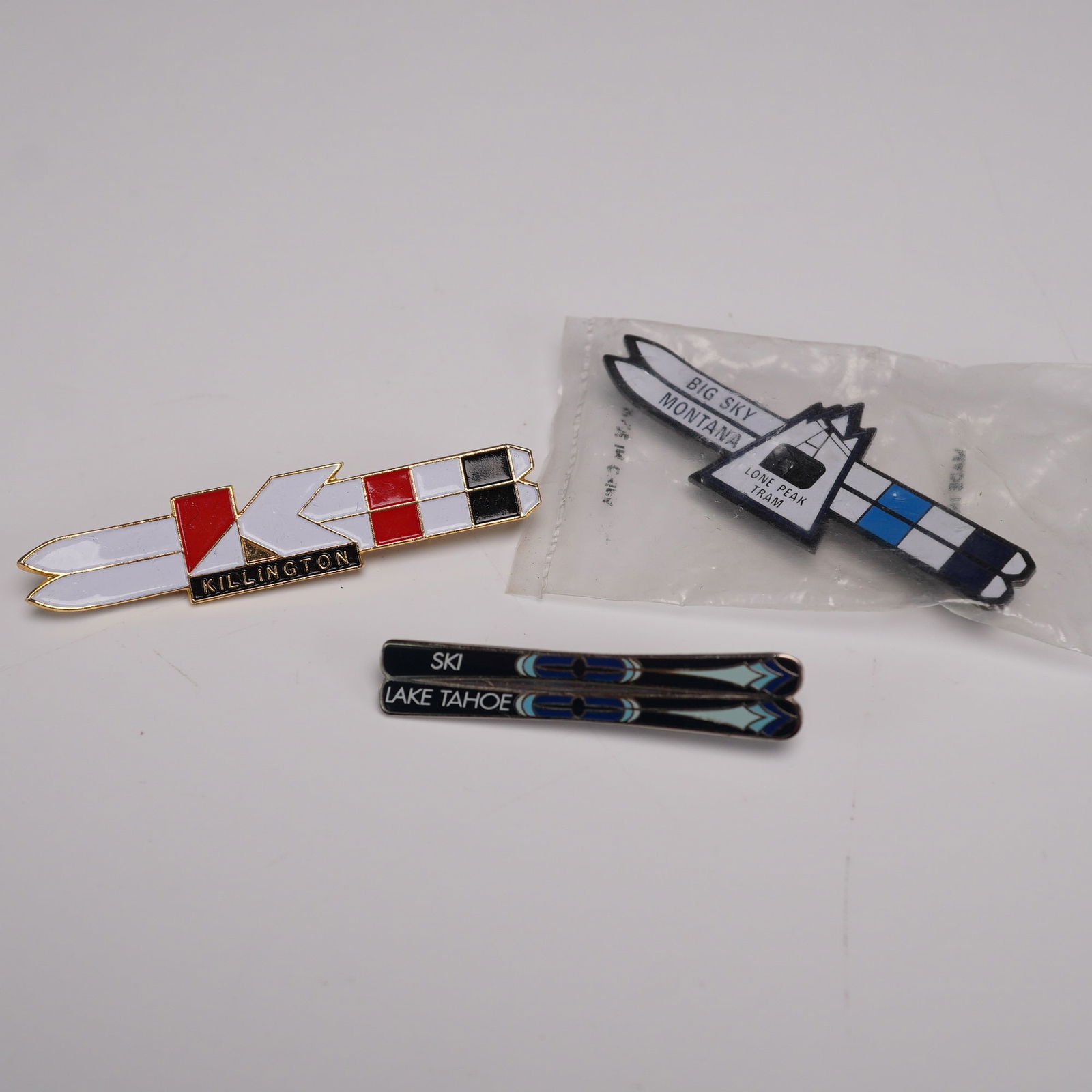 3pc Ski Resort Enamel Pins, Killington, Big Sky, Lake Tahoe: Group of three enamel ski pins featuring various North American ski resorts. Includes a Killington pin designed as crossed skis in red, white, and black; a Big Sky Montana "Lone Peak Tram" pin in orig