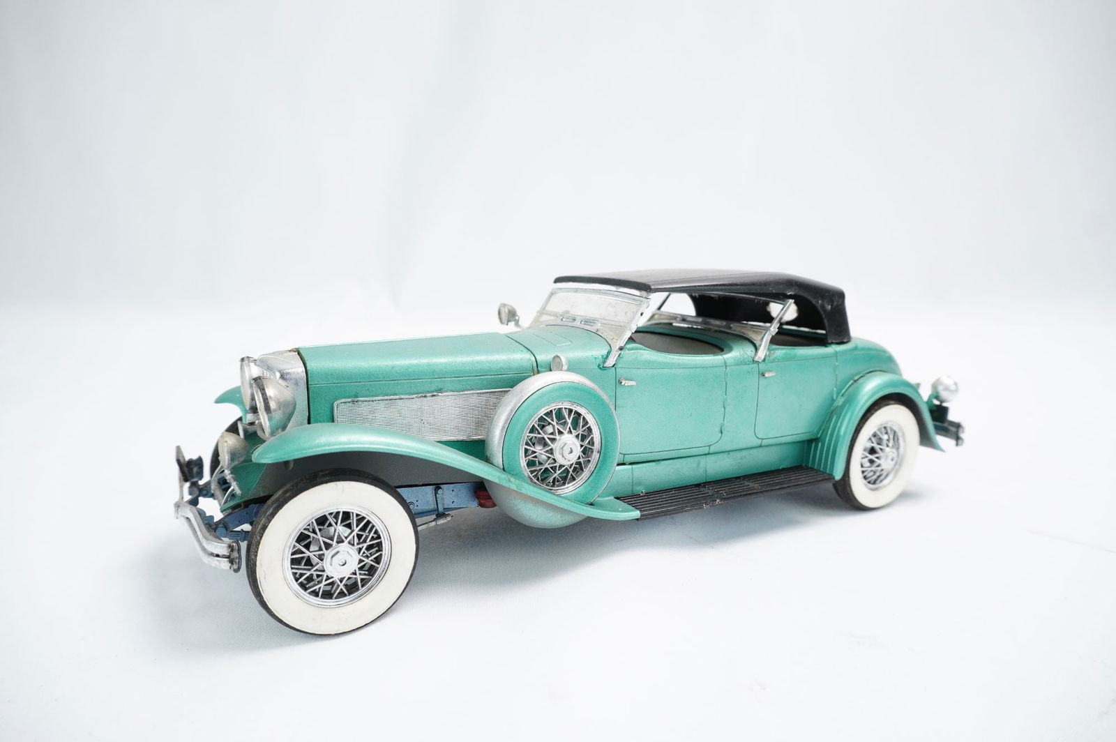 Duesenberg Model J Style Die-Cast Convertible Touring Car: A highly detailed die-cast model car representing a Duesenberg Model J or similar luxury convertible touring vehicle from the American Classic Era (circa 1930s). The model features a metallic teal/aqu