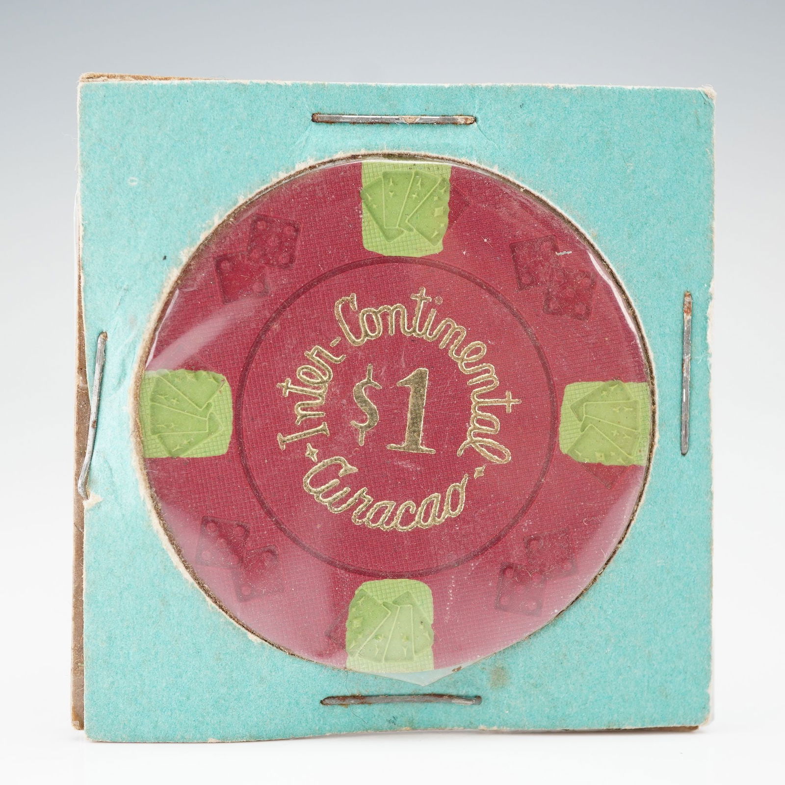 Inter-Continental Curacao Casino 1 Dollar Token: Features a red composite body with embossed green inserts showing playing cards and dice motifs. The obverse and reverse display the inscription INTER-CONTINENTAL CURACAO 1 dollar in gold lettering. T