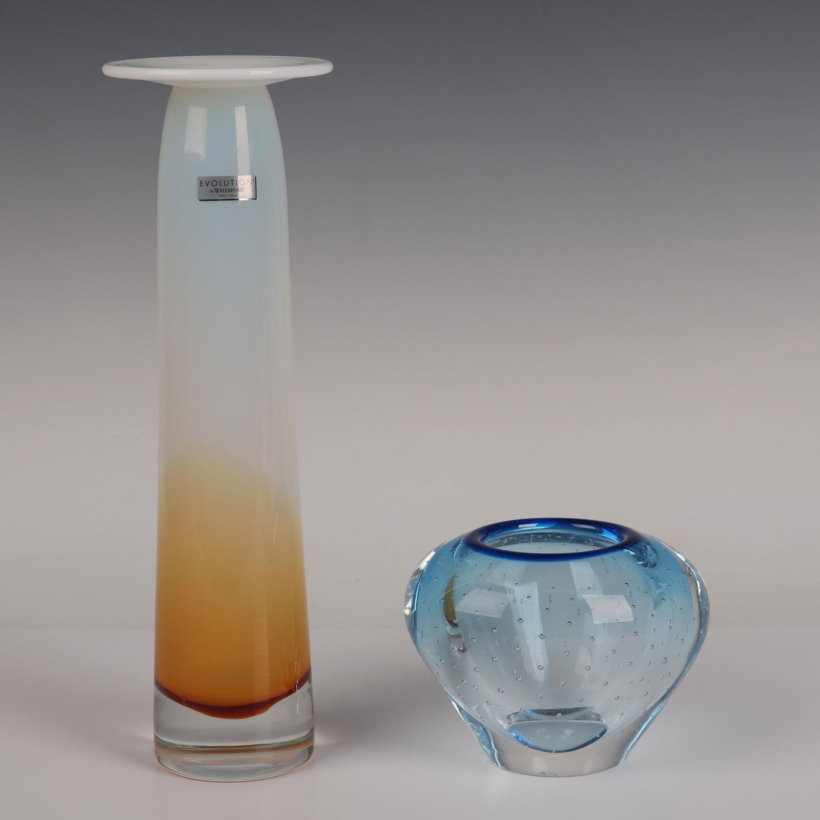 2pc Evolution by Waterford, Candlestick Pillar and Vase: Two beautiful Waterford Crystal Evolution hand-crafted pieces including pillar single light candlestick in opal white color accented with rich amber color at the base. Measures 12"H x 3.75" dia.