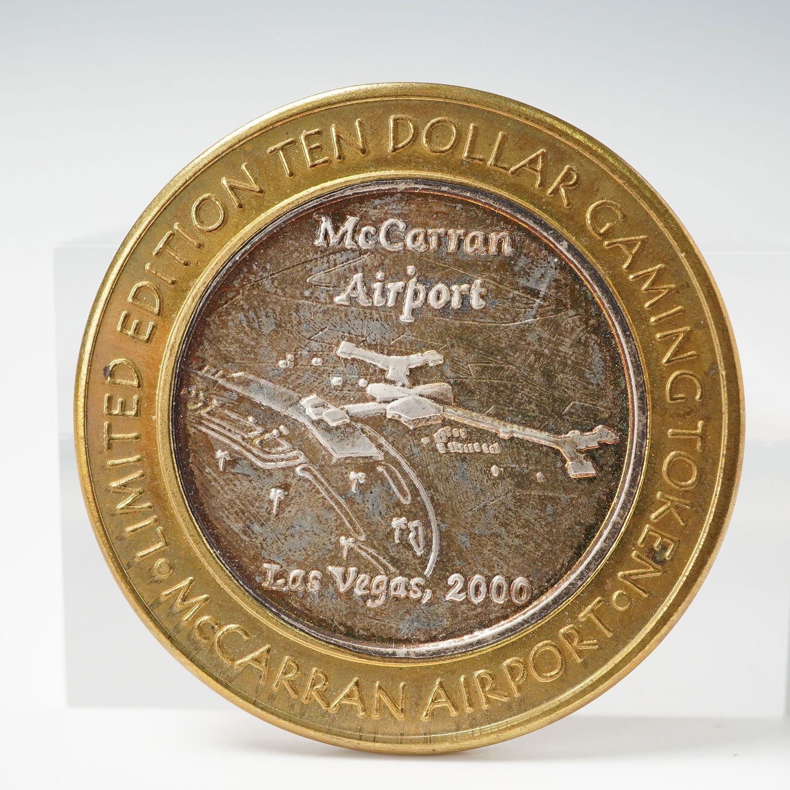 2000 Las Vegas McCarran Airport Ten Dollar Gaming Token: A limited edition ten dollar gaming token issued for McCarran International Airport in Las Vegas, Nevada, dated 2000. The center strike is fine silver surrounded by a brass outer ring. One side featur