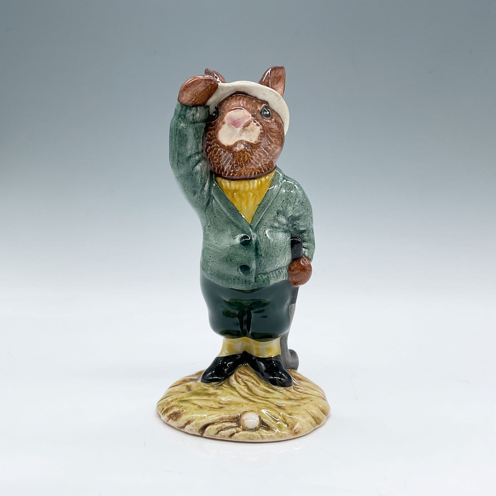 Royal Doulton Bunnykins Figurine, Bogey Bunnykins DB32: This charming Royal Doulton Bunnykins figurine, titled "Bogey Bunnykins," is model DB32 and features the character dressed in a green coat, yellow sweater, and golf attire. The figurine stands 4.25"H