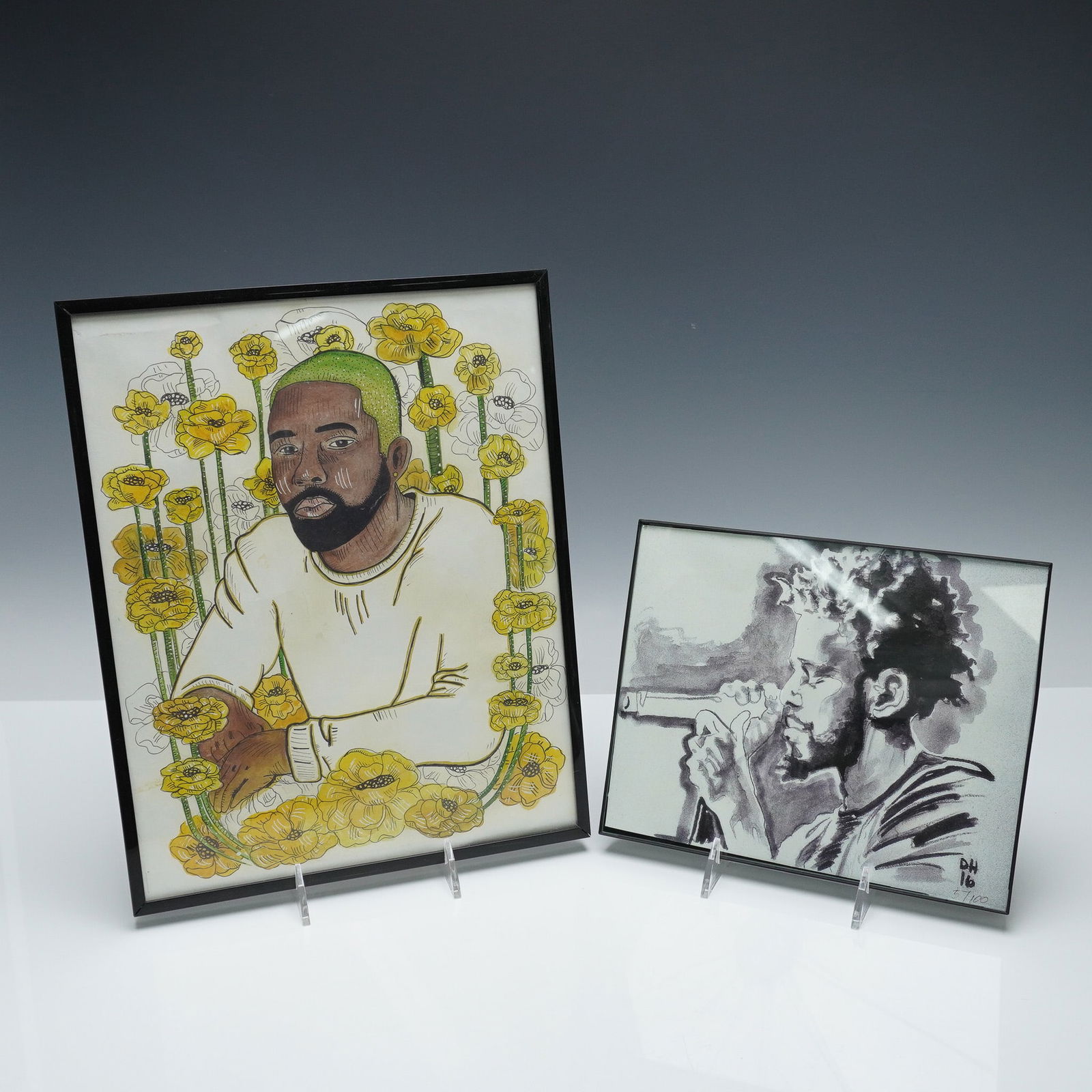 2pc Framed Art Prints, J. Cole and Frank Ocean Portraits: Two framed art prints depicting iconic musical artists J. Cole and Frank Ocean. The J. Cole portrait is rendered in grayscale, showing the rapper holding a microphone in a dynamic, expressive style.