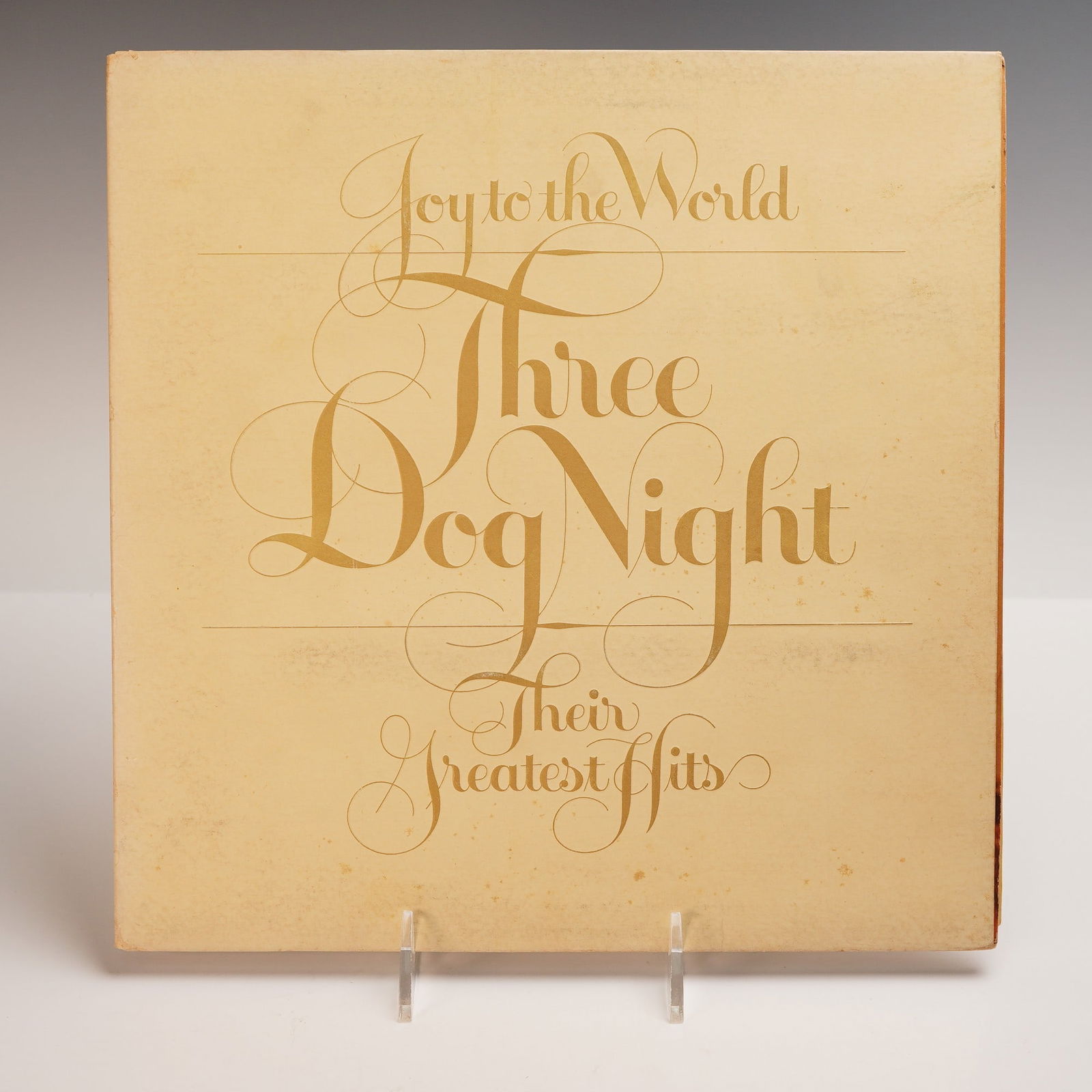 Three Dog Night Vinyl Record, Joy to the World, Their Greatest Hits: A timeless vinyl of Three Dog Night Joy to the World Their Greatest Hits, pressed on black vinyl with a soft cream Dunhill label, enclosed in a classic pale beige sleeve with elegant golden script acr