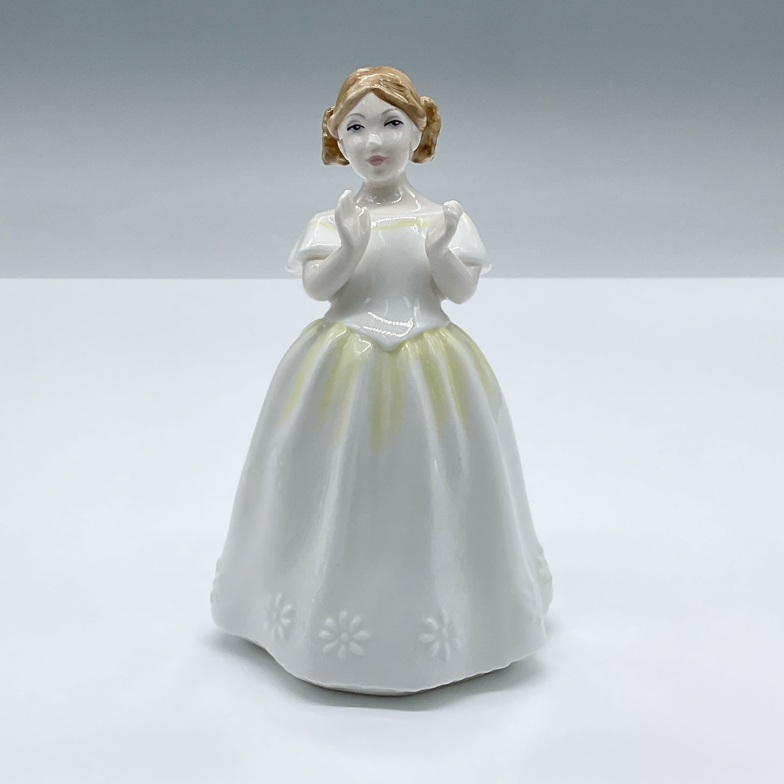 Royal Doulton Bone China Figurine, Catherine HN3451: A lovely figure of a small girl in a white dress clapping. Part of the Child Study series. Royal Doulton backstamp. Artist: Pauline Parsons Issued: 1993 - 1999 Dimensions: 3"L x 3"W x 5"H Country of O