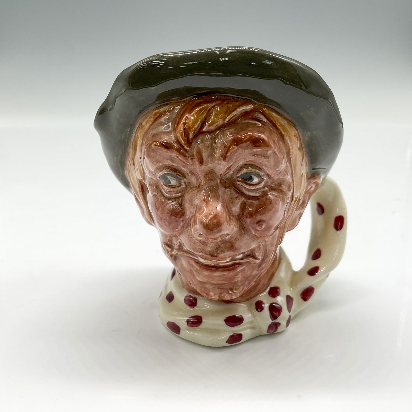 Jarge D6295 - Small - Royal Doulton Character Jug: Green cap; white scarf with red polka-dots. Royal Doulton backstamp. Artist: Harry Fenton Issued: 1950 - 1960 Dimensions: 3.5"H Country of Origin: England