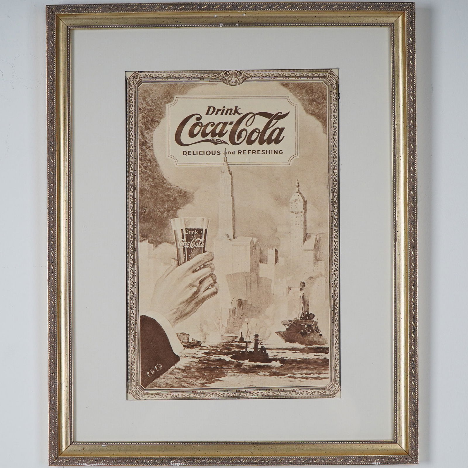 Framed Coca-Cola Advertisement Reproduction Poster with Maritime Scene: A vintage Coca-Cola advertisement poster in sepia tones, professionally matted and framed. The artwork features a detailed illustration of a hand holding a classic Coca-Cola glass with a frothy drink,