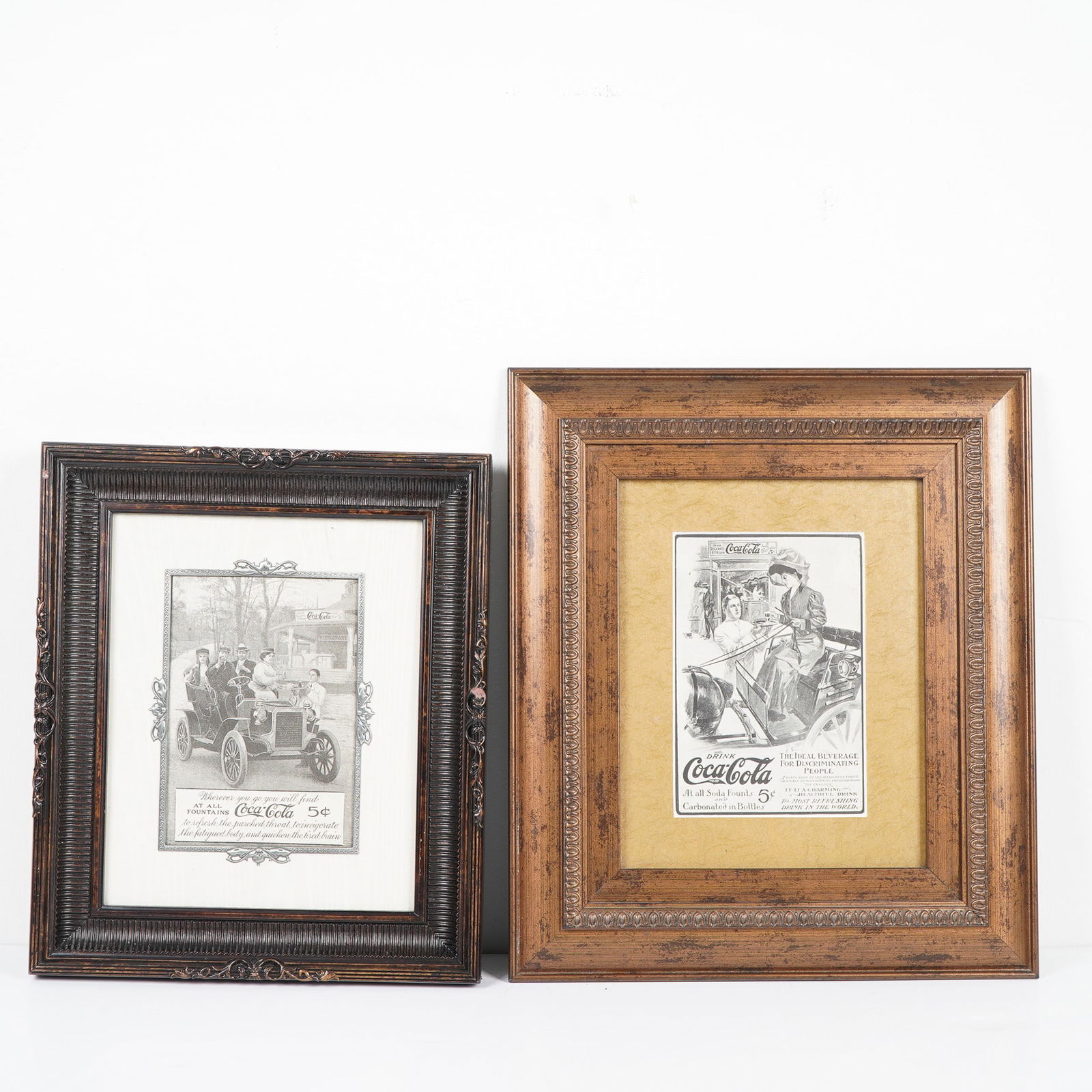 2pc Pair of Framed Reproduction Coca-Cola Automobile Advertisements: A pair of framed reproduction Coca-Cola advertisements featuring early 20th-century automobile scenes, highlighting the brand's deep association with American innovation and lifestyle. Both prints are