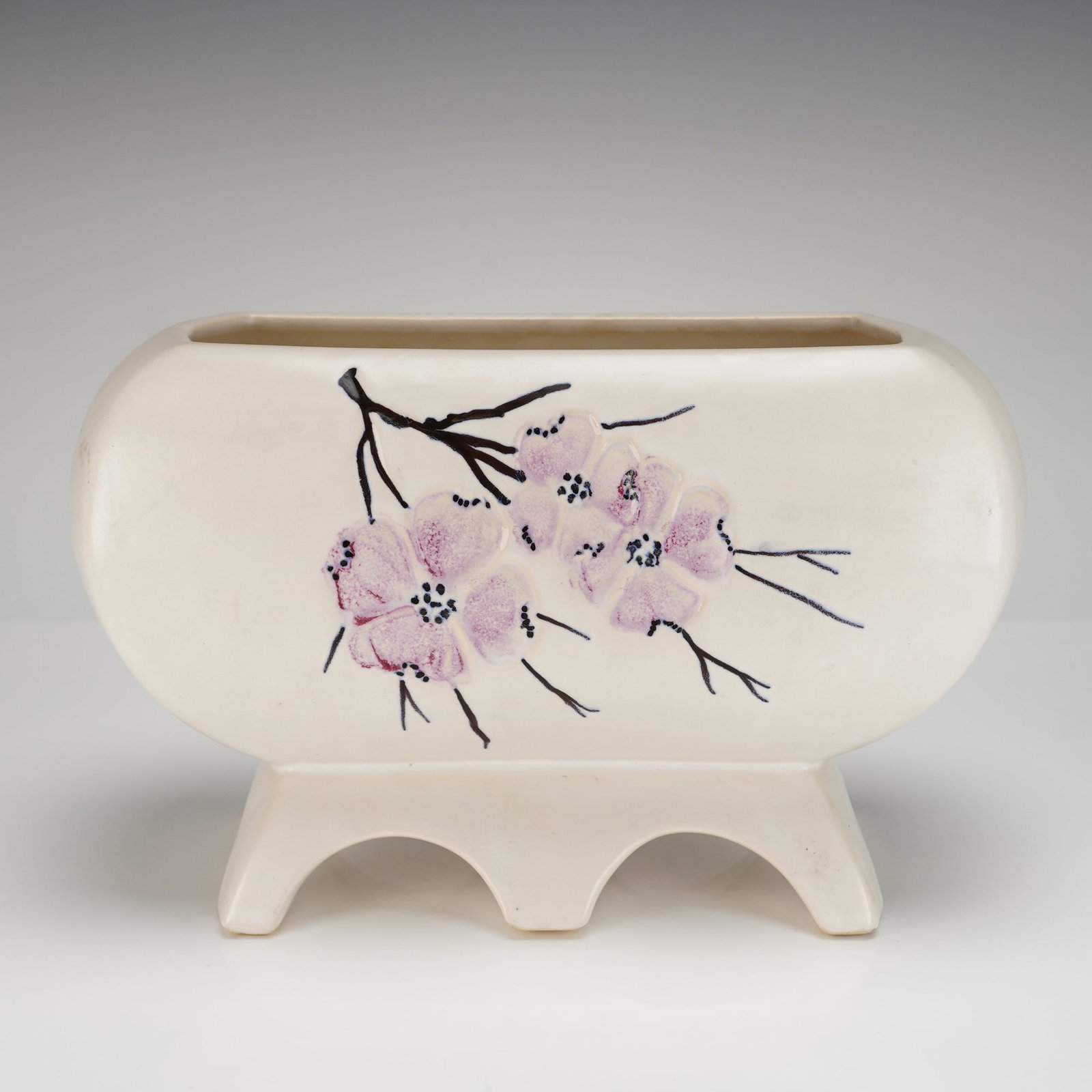 McCoy Pottery Spring Wood Dogwood Blossom Footed Rectangular Planter: A single McCoy Pottery Spring Wood Dogwood Blossom Footed Rectangular Planter vessel, reflecting Mid-Century Modern design. The oblong ceramic body is raised on an integral footed base supported by fo