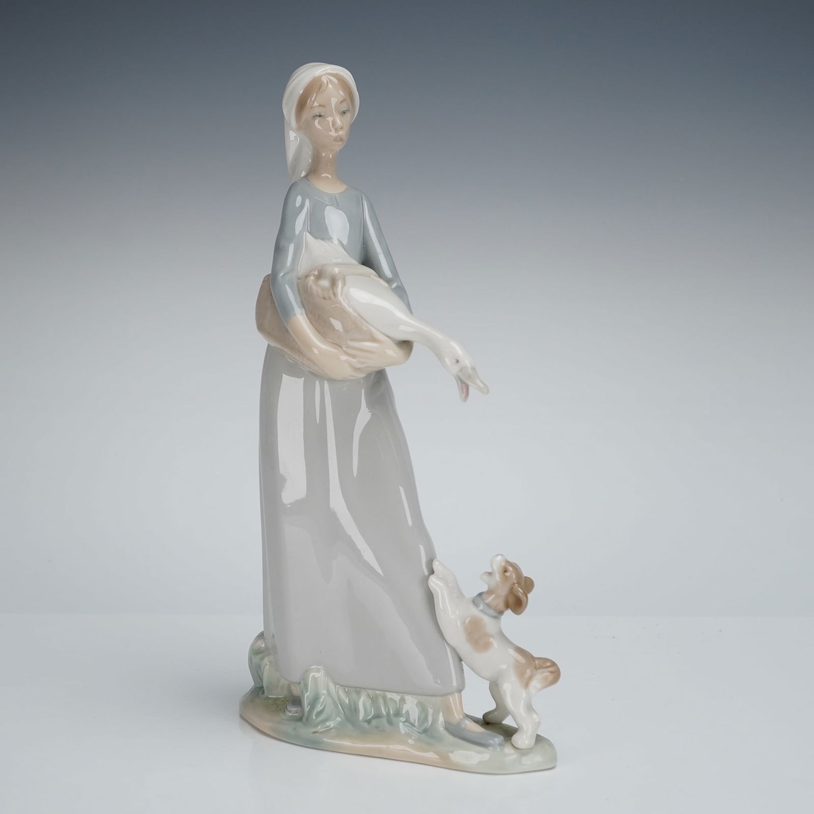 Lladro Figurine Girl With Goose and Dog Model 4866: A single glazed porcelain figurine by Lladro, titled "Girl with Goose and Dog," model number 4866. This Lladro porcelain figurine depicts a young woman standing, dressed in a long, flowing pale grey d