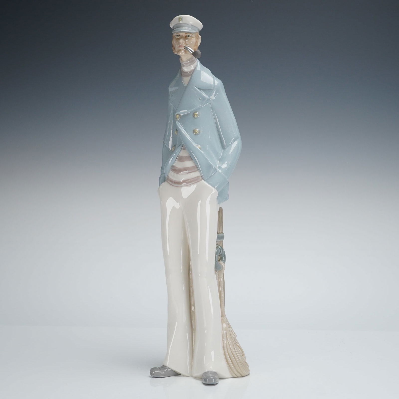 Lladro Porcelain Sea Captain Sculpture 4621: A Lladro porcelain figurine, titled "Sea Captain" (Model #4621). The glazed figure depicts a stylized male figure in a nautical theme, standing and leaning against a tan-colored wooden mooring post wi