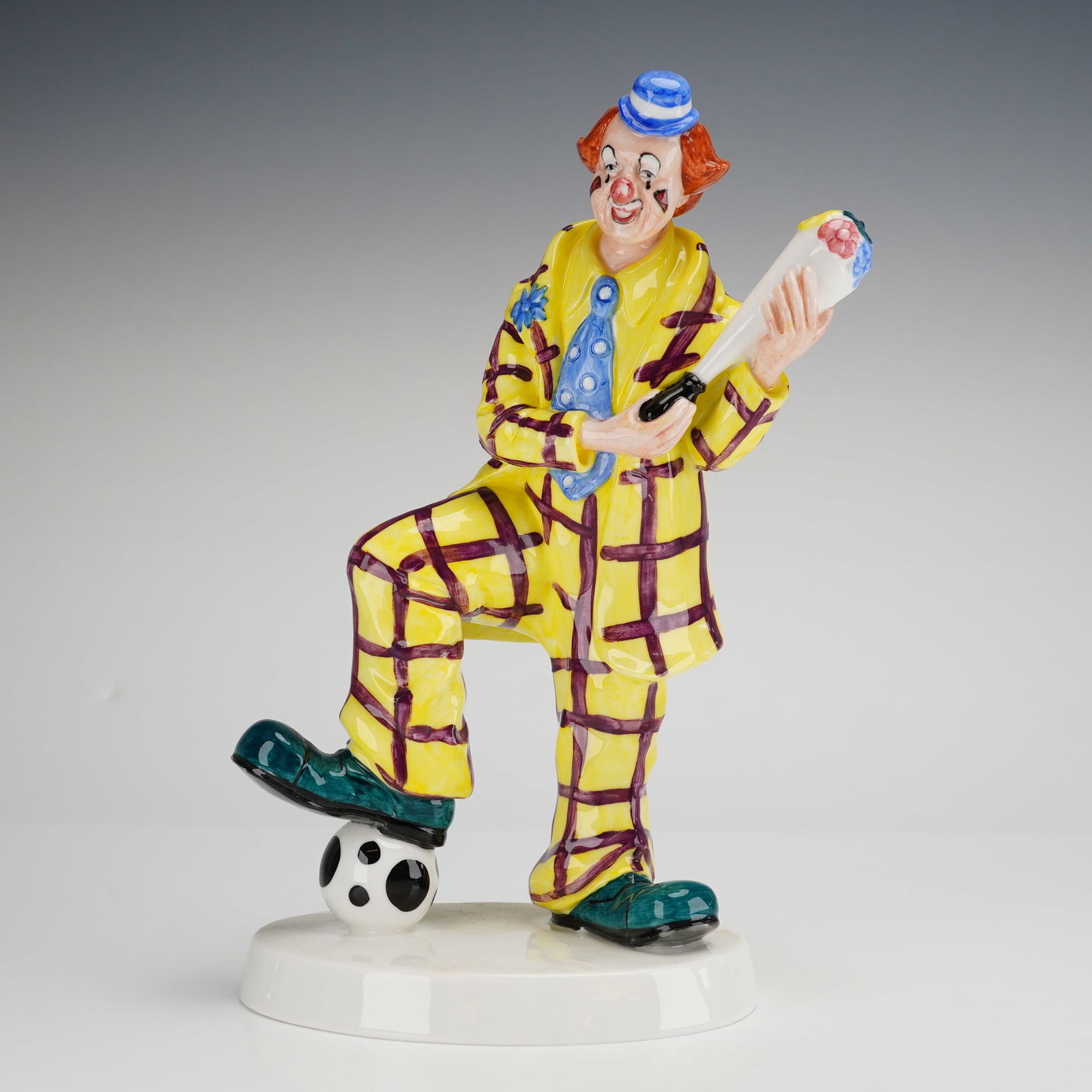 Coalport Cavalcade of Clowns Series Figurine, Auguste's Bouquet: The figure depicts a clown character dressed in a yellow and purple plaid suit with a blue polka-dot necktie and oversized green shoes. He is modeled with ginger hair and a small blue and white stripe