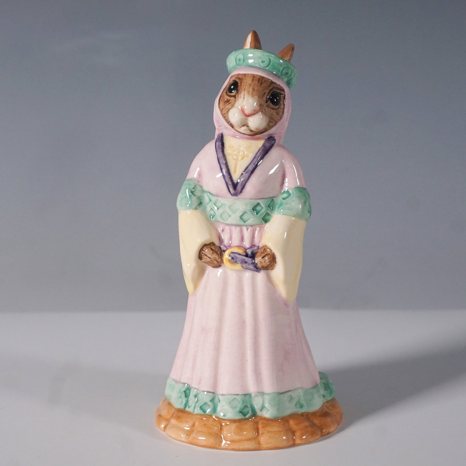 Royal Doulton Bunnykins Figurine, Maid Marion DB245: This Royal Doulton Bunnykins figurine, Maid Marion DB245, is part of the Robin Hood Collection. Handcrafted from fine bone china, this charming piece depicts Maid Marion in a flowing pink gown with gr