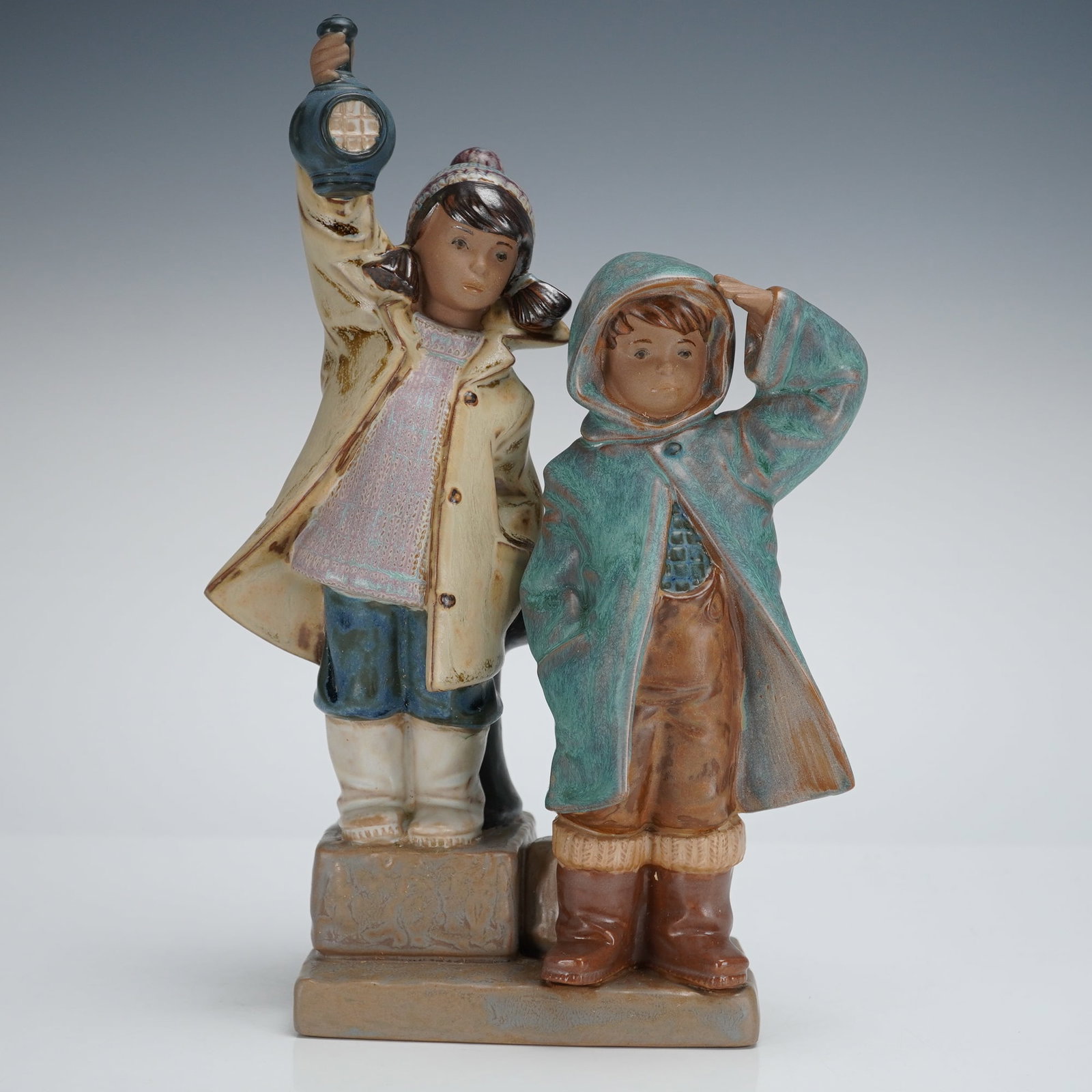 Lladro Porcelain Figurine Ahoy There 1012173: A Lladro porcelain figurine, titled "Ahoy There" (1012173), depicting two children dressed in outerwear standing on a stepped base resembling a dock or seawall structure. The girl is shown holding a l