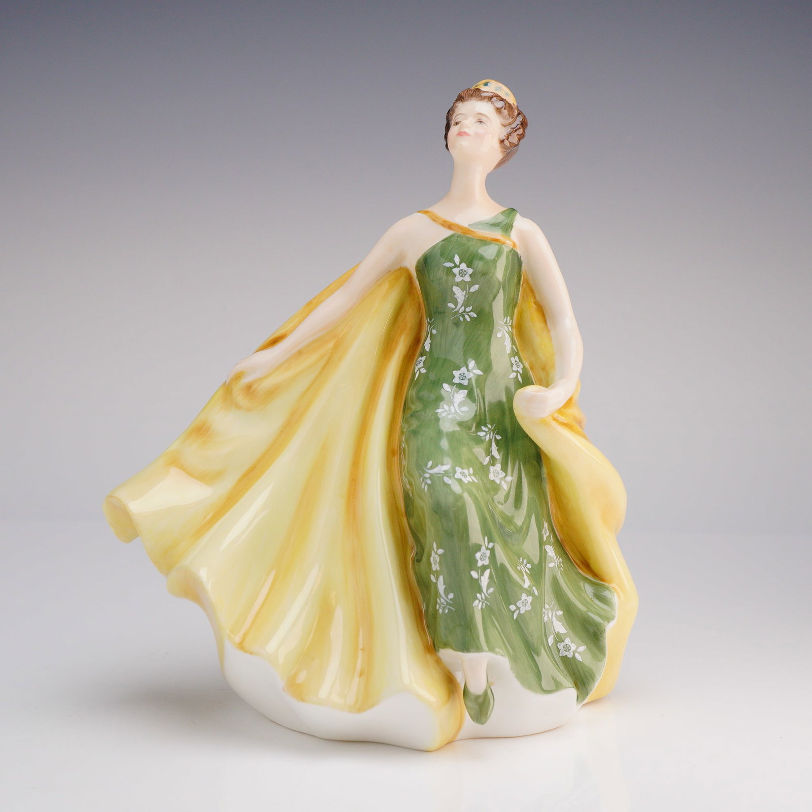 Royal Doulton Alexandra HN2398 Figurine: The piece reflects a mid-20th-century decorative style, copyrighted 1969. The female figure is modeled dynamically, captured in an elaborate pose, wearing a green dress patterned with white flowers an