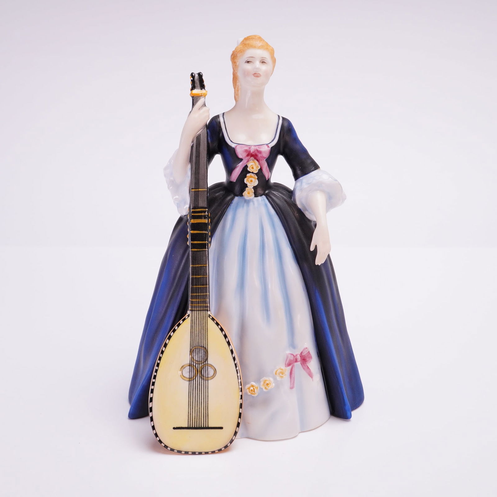 Royal Doulton Figurine, Chitarrone HN2700: A Royal Doulton bone china figurine is part of the Lady Musicians series. The piece depicts a standing woman in 18th-century attire holding a large lute-like instrument known as a chitarrone. The figu