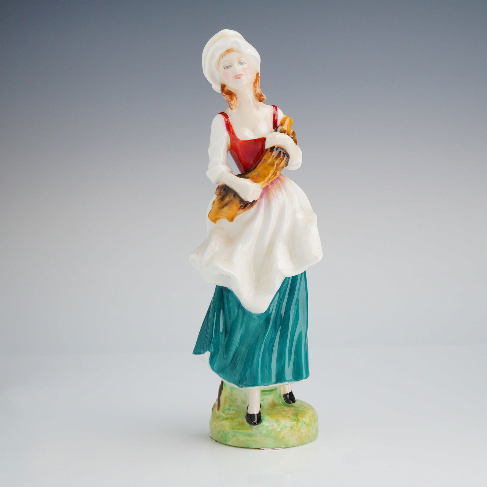 Royal Doulton Figurine, Lizzie HN 2749: A Royal Doulton figurine, modeled by Douglas V Foote and dated 1987, depicting a woman in a white, red, and teal dress holding a bundle of wood. Royal Doulton backstamp on base. Dimensions: 8.50"H Wei