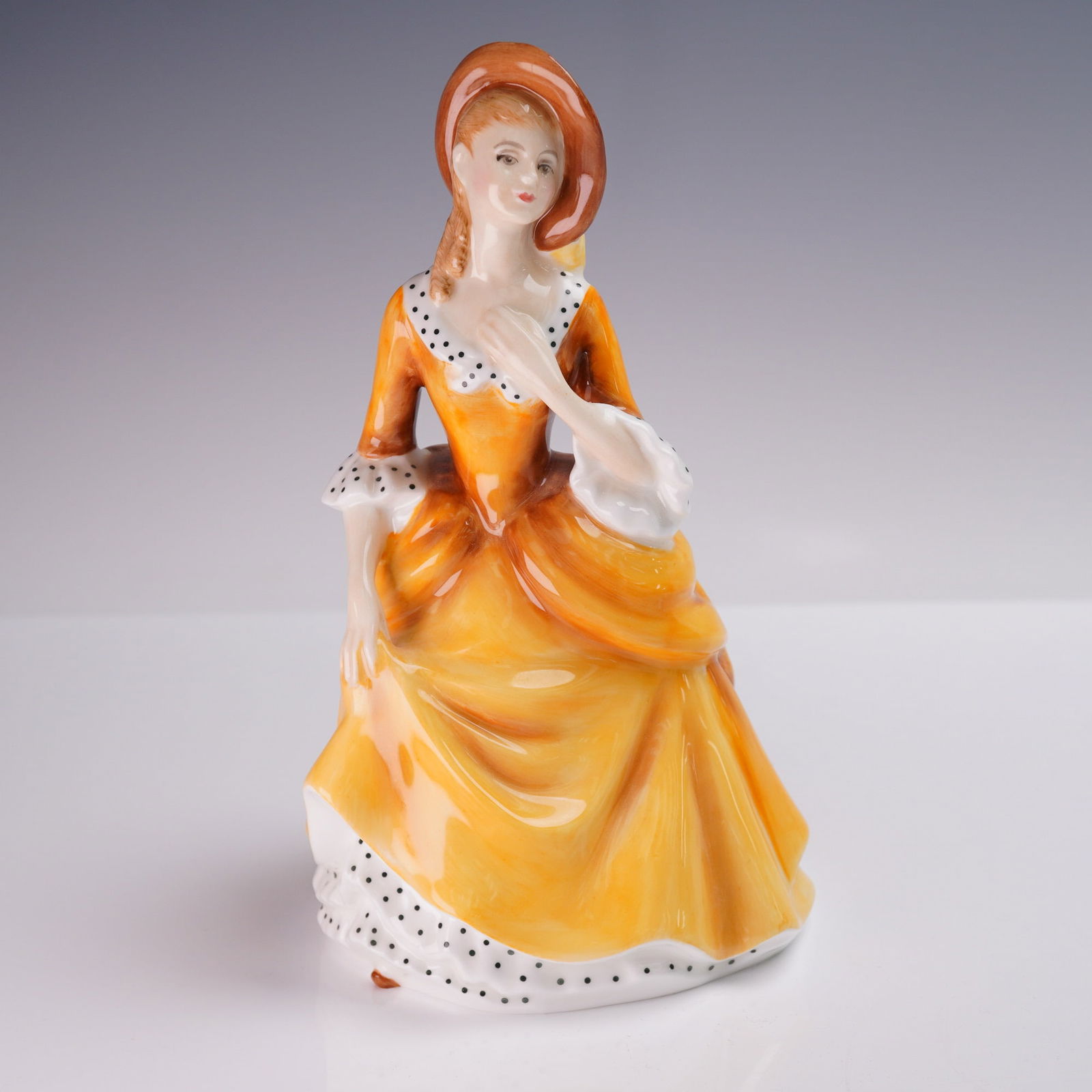 Royal Doulton Figurine, Sandra HN2275: A Royal Doulton bone china figurine titled Sandra, model HN2275, designed by Peggy Davies and issued in 1968. The hand-decorated figure portrays a young woman in a bright golden orange gown with black