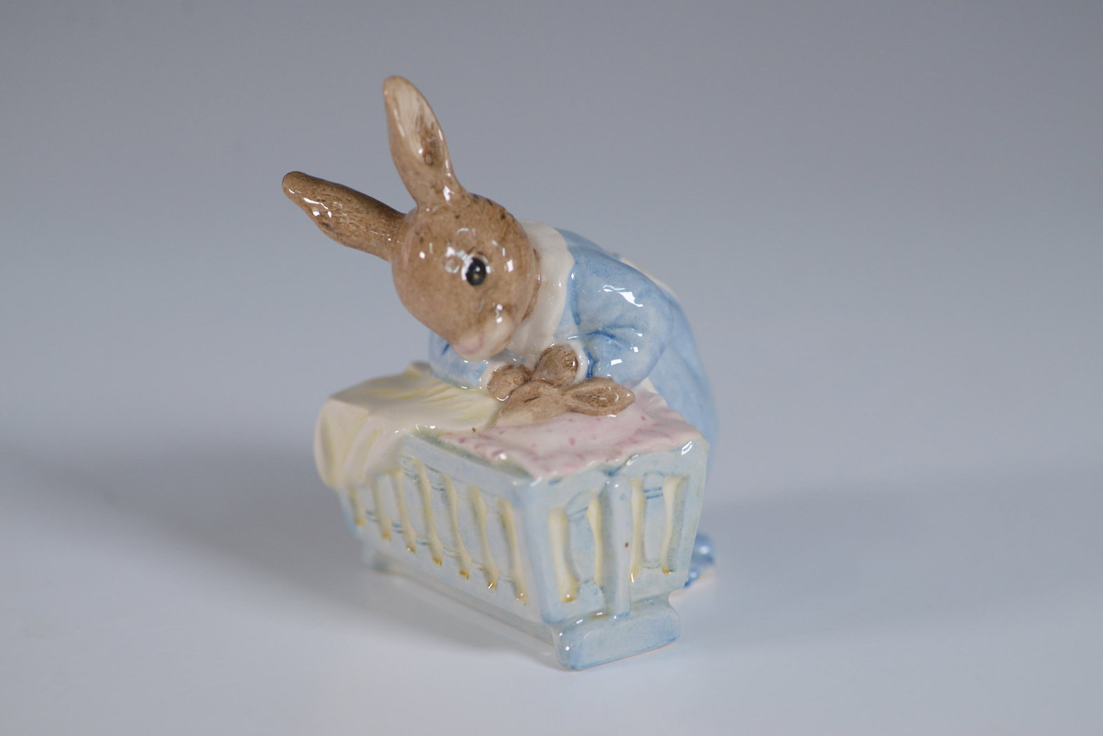 Royal Doulton Bunnykins Figurine, New Baby DB 158: This charming Royal Doulton Bunnykins New Baby figurine DB 158 captures a tender moment as a mother bunny gazes lovingly into a crib. Crafted in fine bone china, this collectible was issued in 1995 an
