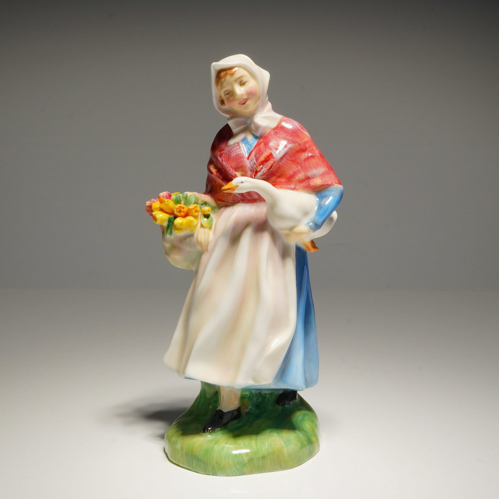 Royal Doulton Figurine Market Day HN 1991: A Royal Doulton Figurine market day hn1991 bone china figurine of a woman in white, red, and blue holding a goose and a basket of yellow flowers, marked on the base with the Royal Doulton logo, "MADE