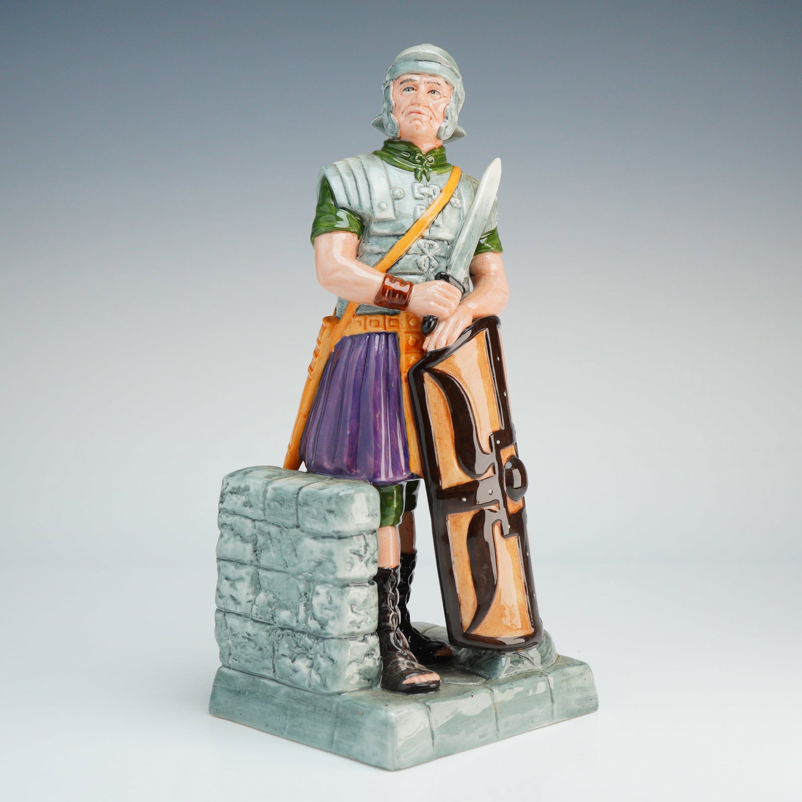 Royal Doulton Figurine The Centurion HN2726: A Royal Doulton ceramic figurine titled The Centurion, model number HN2726, designed by William K. Harper. The figure depicts a Roman soldier in military dress, including a silver-toned helmet, segmen