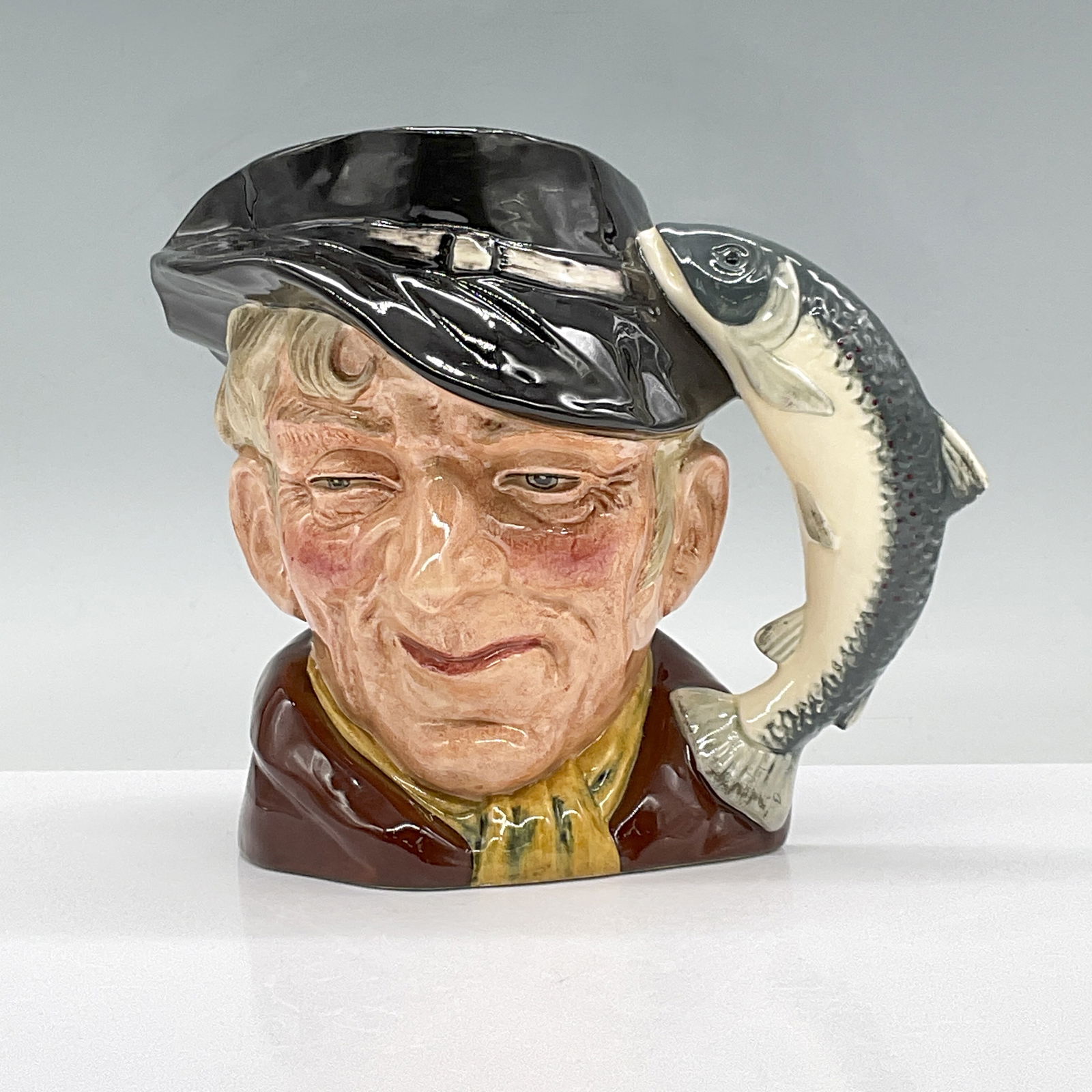 Royal Doulton Large Character Jug, The Poacher D6781: This glossy character jug is featured in the new colorway with a black hat, brown coat and yellow scarf. Royal Doulton backstamp. Artist: Max Henk Dimensions: 7.75"L x 5.75"W x 7"H Issued: 1987-1989 C