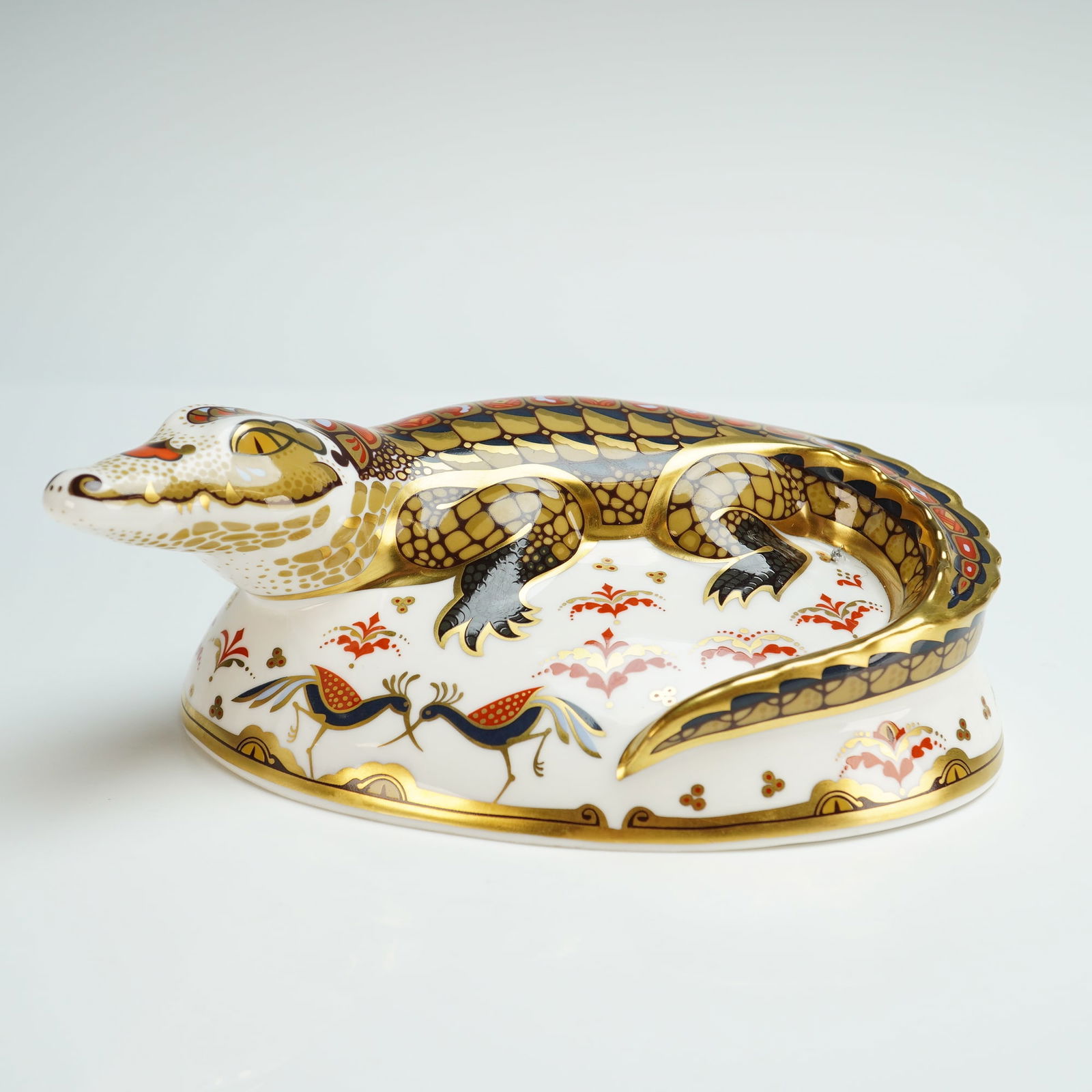 Royal Crown Derby Gold Paperweight, Signature Edition Crocodile: The Crocodile designed as an exclusive Gold Signature Edition for the Guild of Specialist China and Glass Retailers. The figurine depicts a reclining crocodile positioned on an oval base, decorated in
