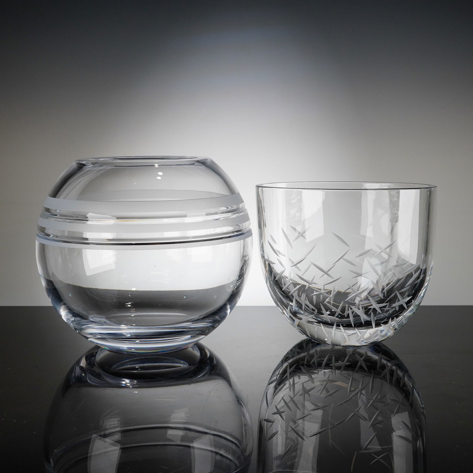 2pc Kate Spade New York Crystal Rose Bowls: A duo of contemporary clear crystal rose bowls by Lenox for Kate Spade New York. It includes one Library Stripe rose bowl of spherical form, featuring three horizontal frosted bands encircling the cen