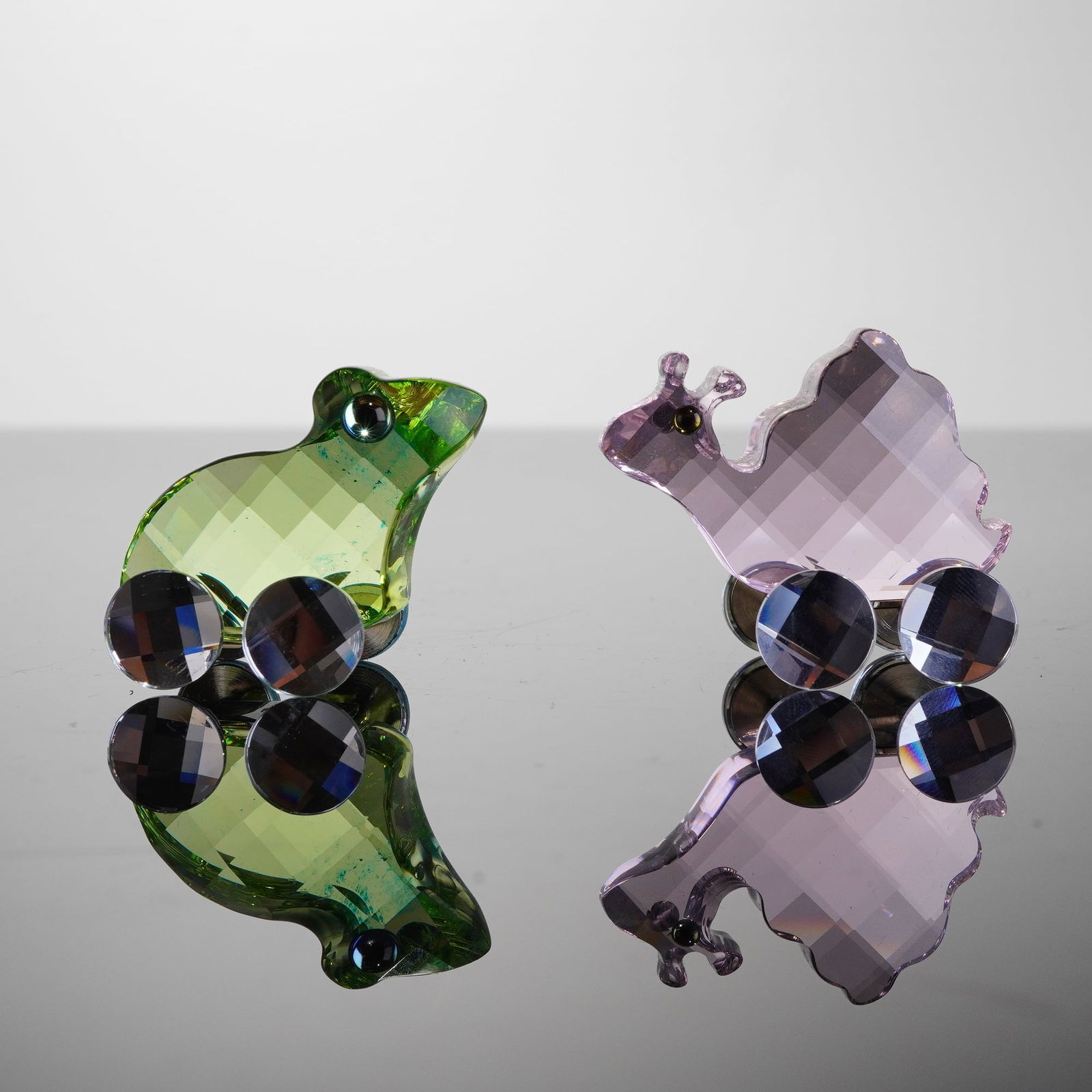2pc Swarovski Crystal Figurines, Fred the Frog & Susie the Snail: The 2pc collection features animal miniatures executed in a highly faceted crystal style, mounted on wheeled metal chassis. Fred the Frog is rendered in green crystal, and Susie the Snail is rendered