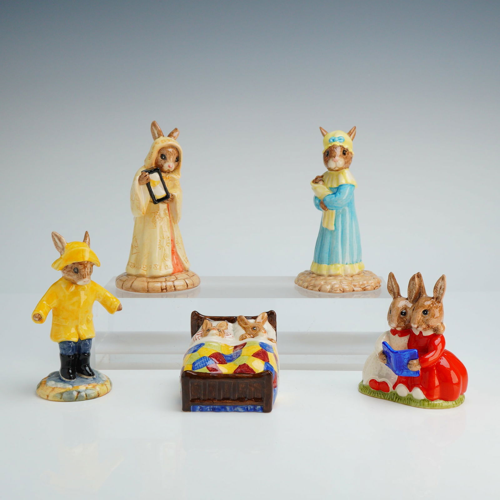 5pc Royal Doulton Porcelain Bunnykins Figurines: The group includes Rainy Day (DB 147) wearing a yellow slicker and boots, Sands of Time (DB 229) holding an hourglass, Judy Bunnykins (DB 235) in a blue dress, Sleepy Time (DB 15) depicting two rabbit