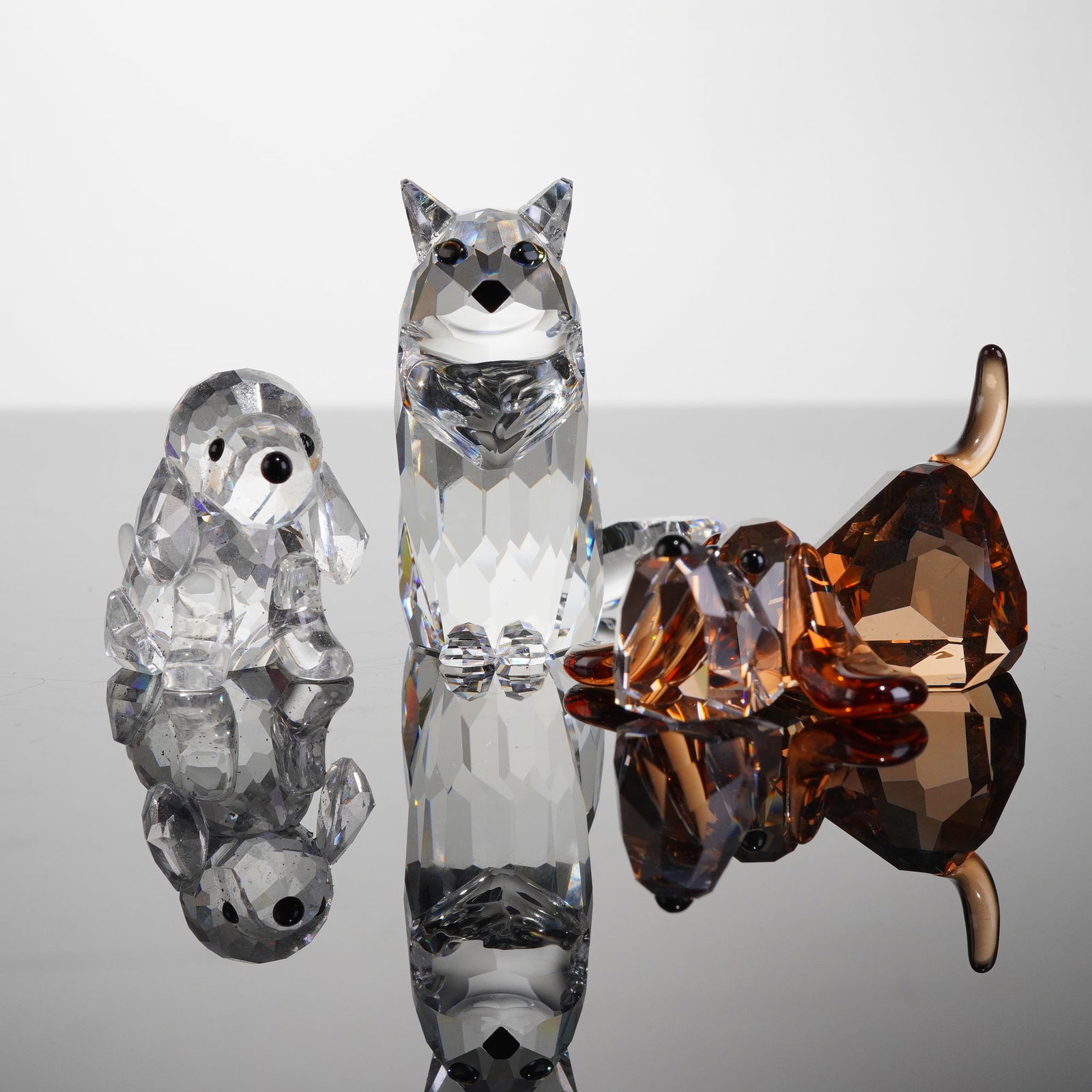 3pc Swarovski Crystal Animal Figurines, Dogs & Cat: The collection includes pieces identified as part of the Lovlots Gang of Dogs series. The figures include the Lovlots Peppino Basset Hound (935720), rendered in amber/brown crystal, a Beagle Puppy Sit