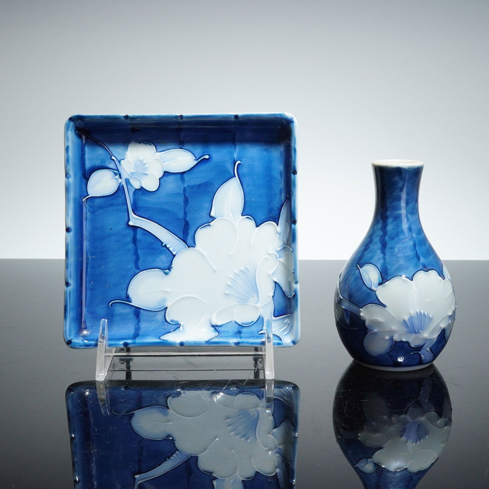 2pc Japanese Blue and White Porcelain Plate and Small Bottle Vase Set: A two-piece porcelain set, comprising a square dish and a small bottle vase (tokkuri), executed in the Japanese Sometsuke technique. The porcelain is decorated in underglaze cobalt blue and white rese